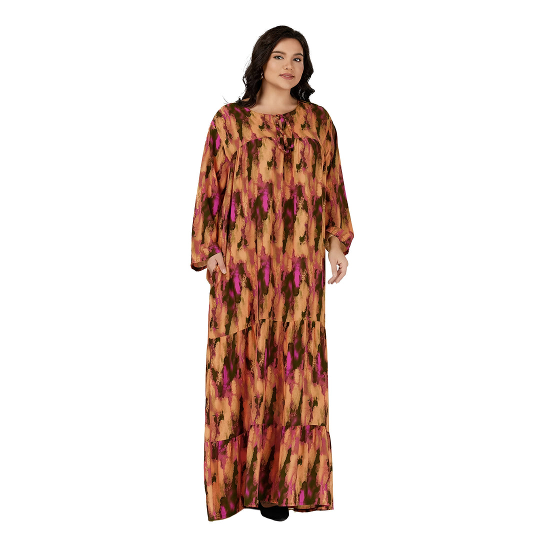 Une femme porte une robe longue à manches longues, à imprimé abstrait orange et rose. La robe est ample et possède un col rond.