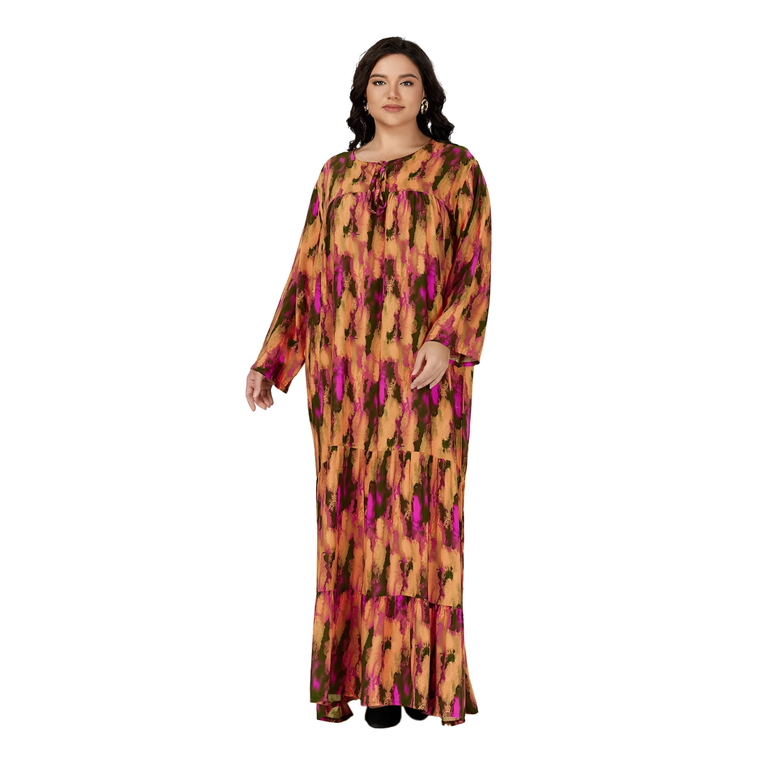 Une femme porte une longue robe musulmane à manches longues avec un imprimé orange, vert et rose. La robe est ample et fluide, et elle a une encolure ronde. La femme a les cheveux noirs et porte des boucles d'oreilles dorées.