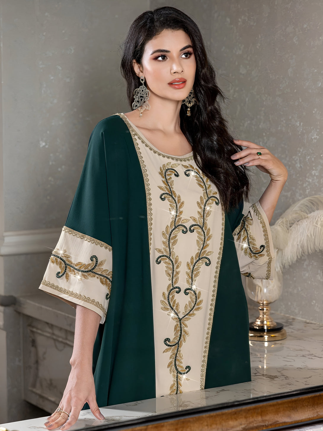 Une femme portant une robe verte et beige avec des broderies dorées. La robe est élégante et idéale pour les occasions spéciales.