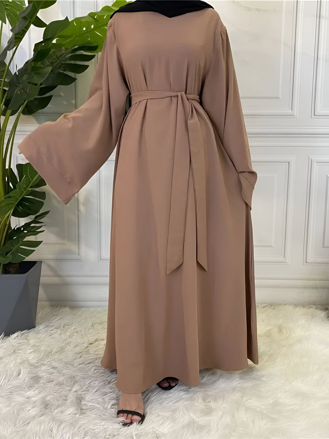 Une robe abaya marron à manches longues et une ceinture. La robe est ample et fluide.