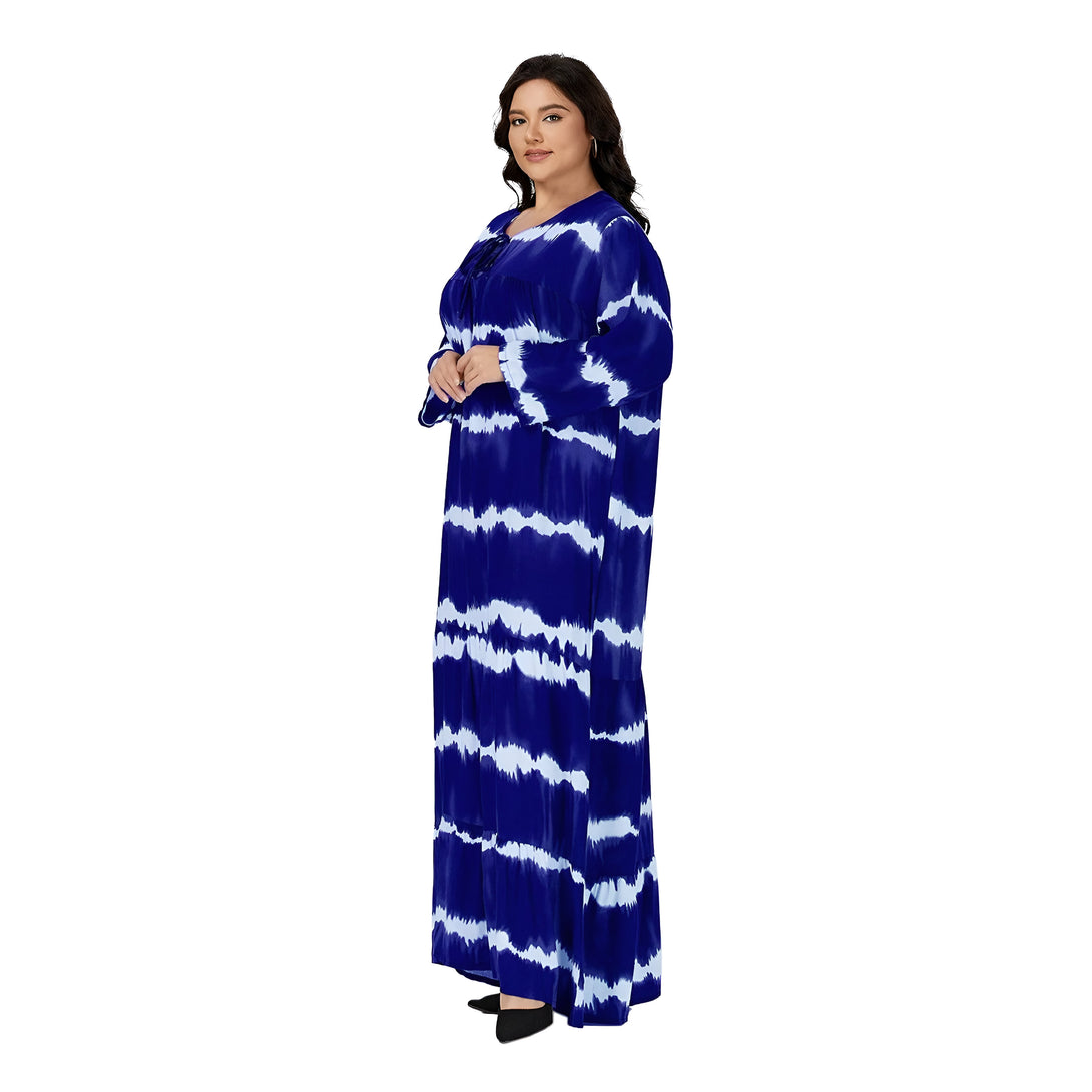 Une femme porte une robe longue bleu marine avec des rayures blanches. La robe est de style tie-dye et a des manches longues. La femme porte des chaussures noires.