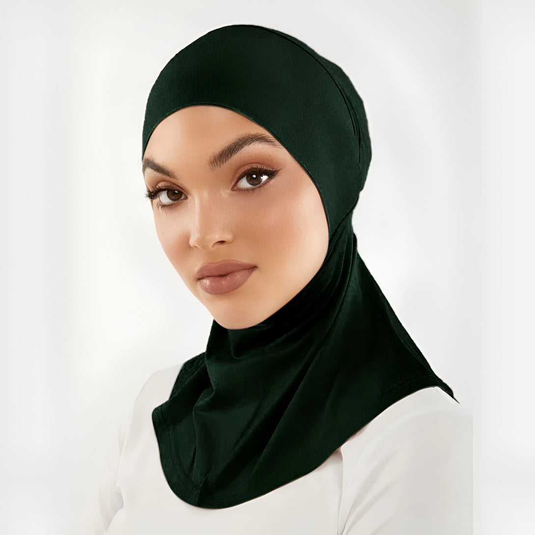 Une femme porte un hijab vert foncé. Le hijab est fait d'un tissu doux et confortable. Il est idéal pour les occasions spéciales ou pour la vie de tous les jours.