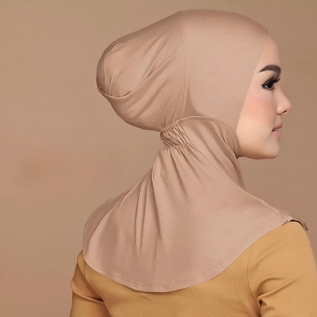 Une femme portant un hijab beige en coton extensible avec une fermeture éclair à l'arrière du cou.