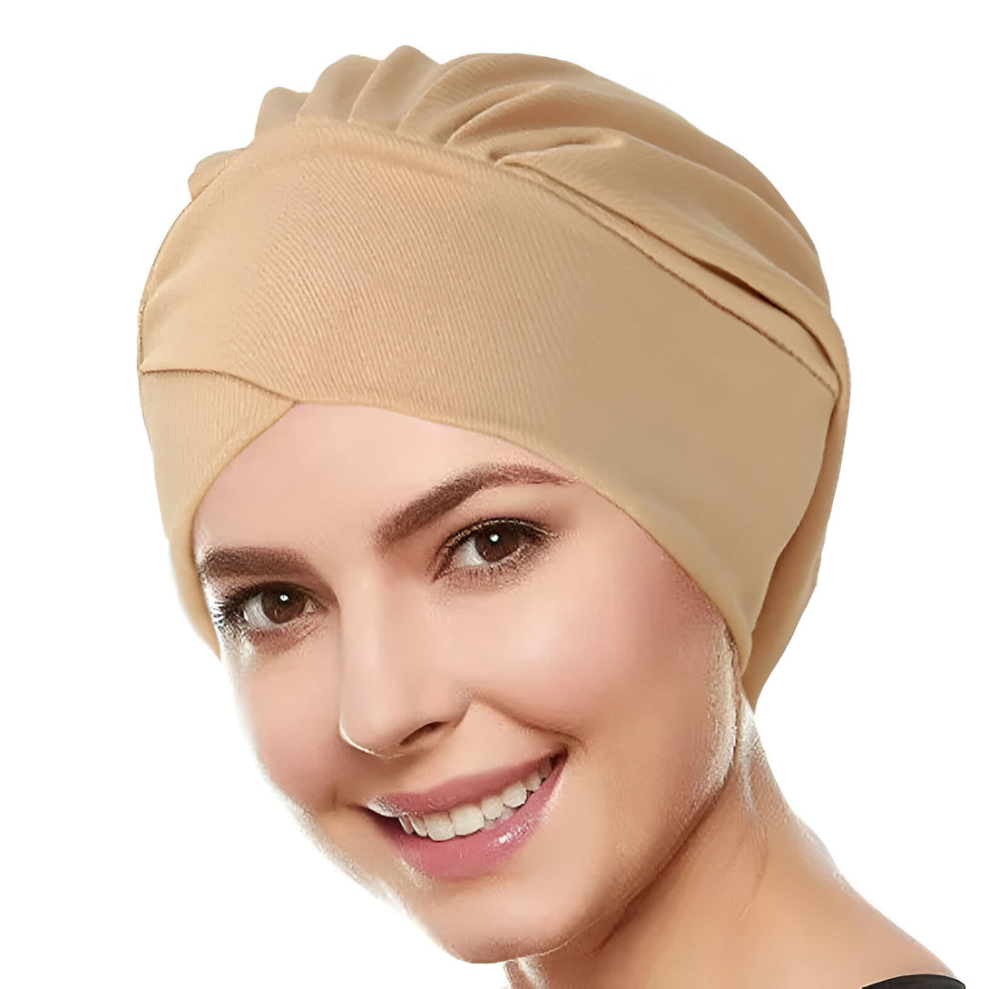 Une femme souriante portant un turban beige en coton. Ce turban est parfait pour les femmes musulmanes qui souhaitent un look élégant et confortable.