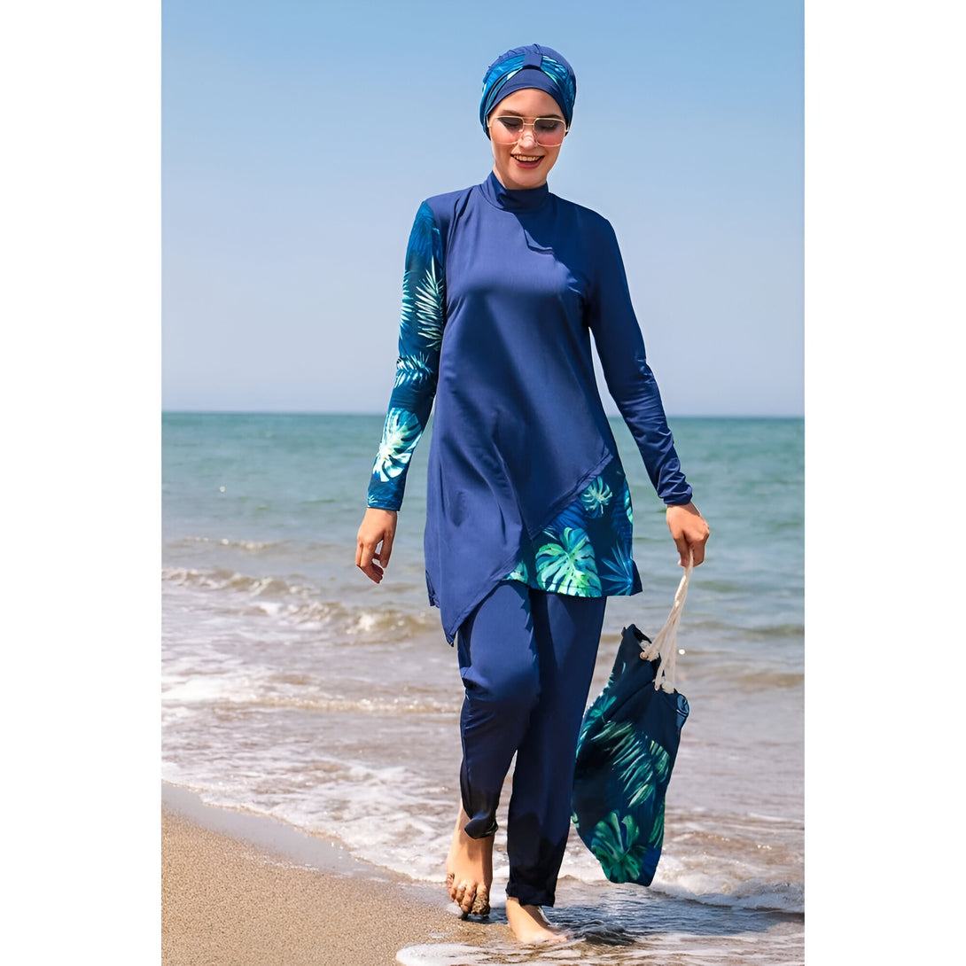 Une femme portant un maillot de bain islamique bleu avec un motif tropical sur la plage.