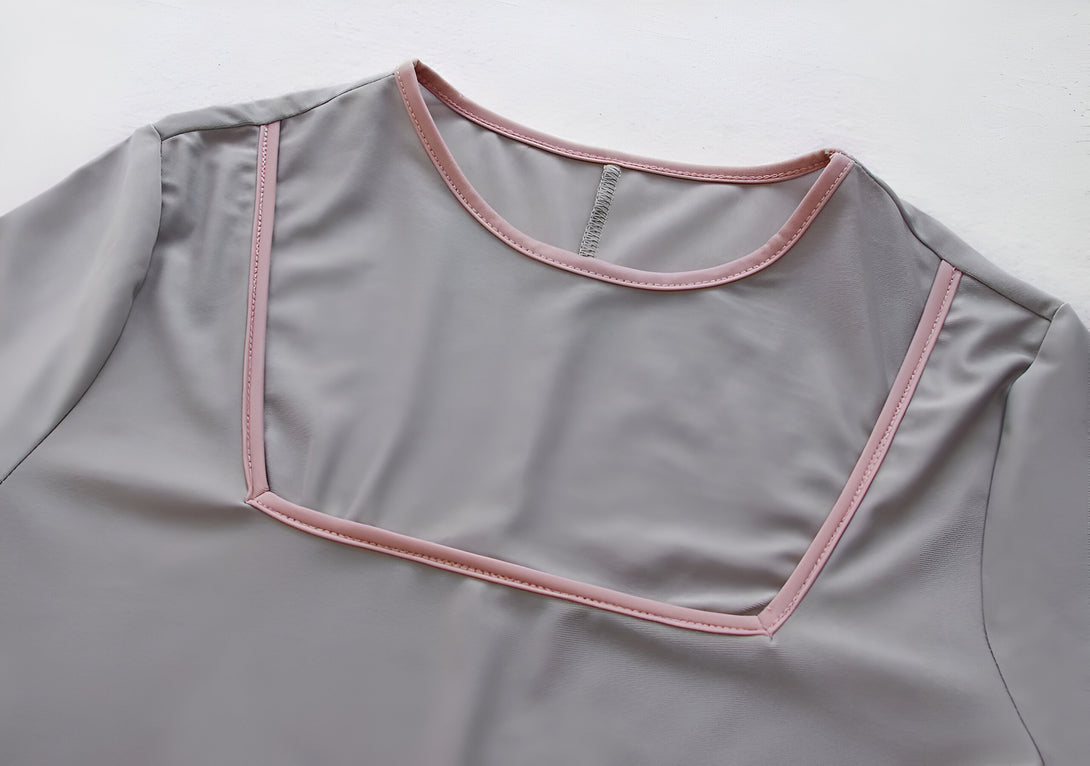 Détail du col d'une robe grise à manches longues avec une bordure rose.  Vêtement musulman élégant pour femme.