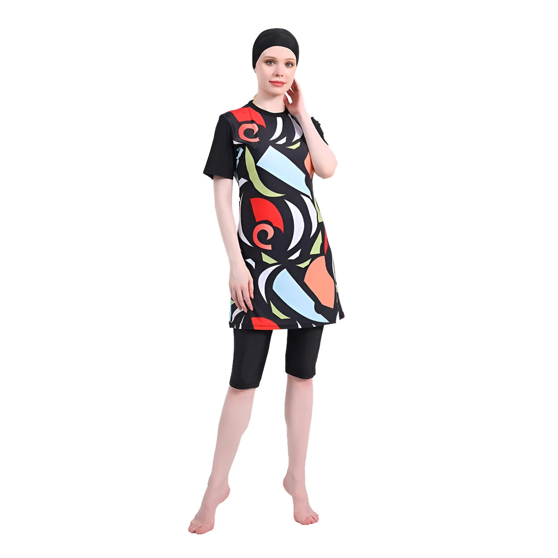 Une femme portant un maillot de bain musulman noir avec un motif abstrait coloré, comprenant une tunique à manches courtes et un pantalon long.