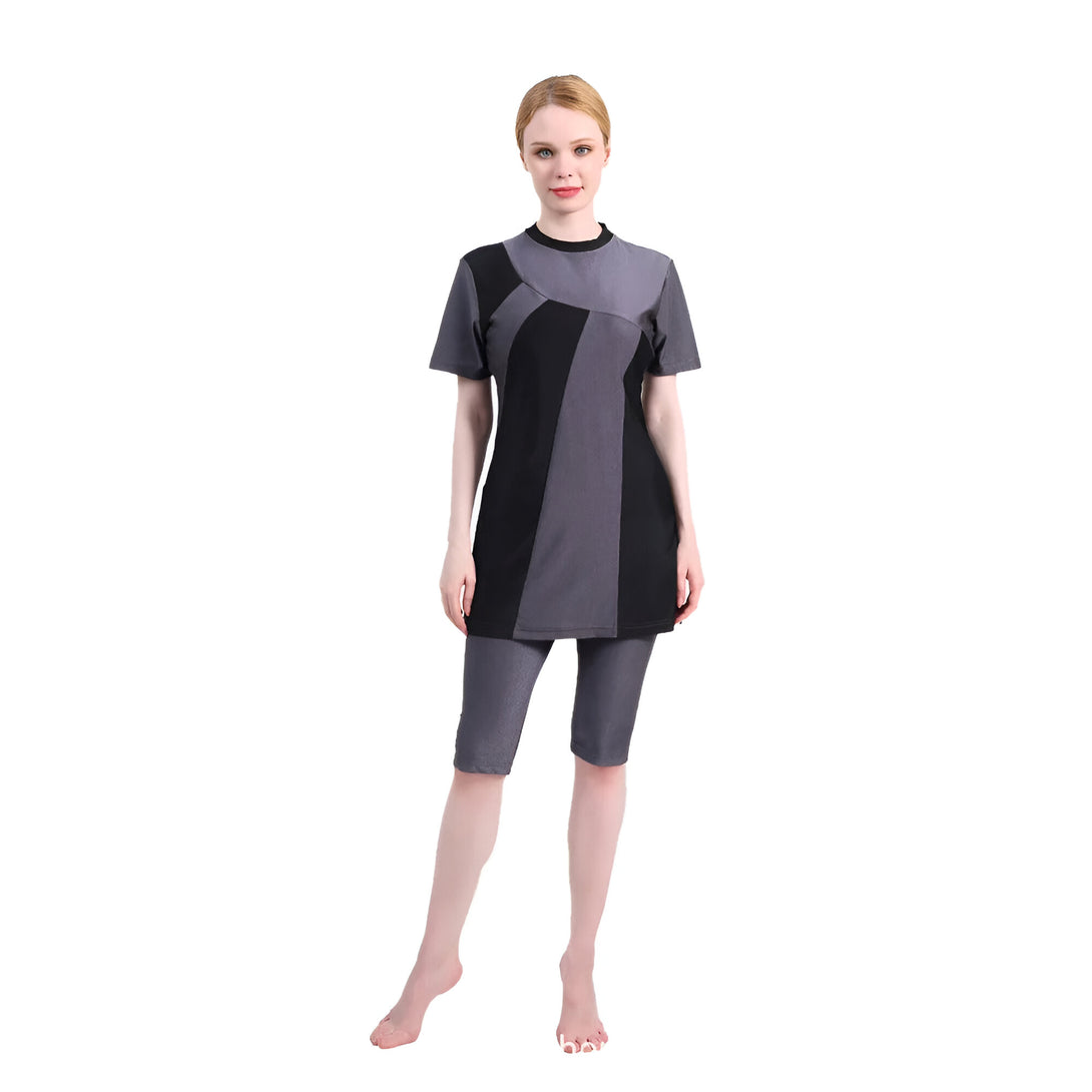 Une femme portant un maillot de bain musulman gris et noir à manches courtes et pantalon long.