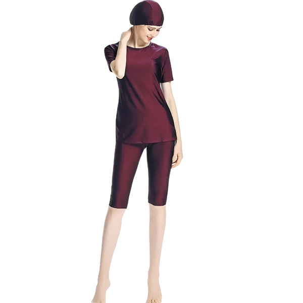 Une femme portant un maillot de bain musulman bordeaux avec un bonnet assorti. Le maillot de bain est composé d'un haut à manches courtes et d'un pantalon long.