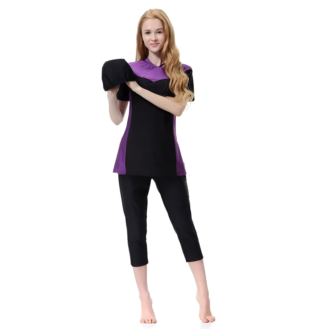 Une femme portant un maillot de bain musulman noir et violet, avec un bonnet de bain noir.