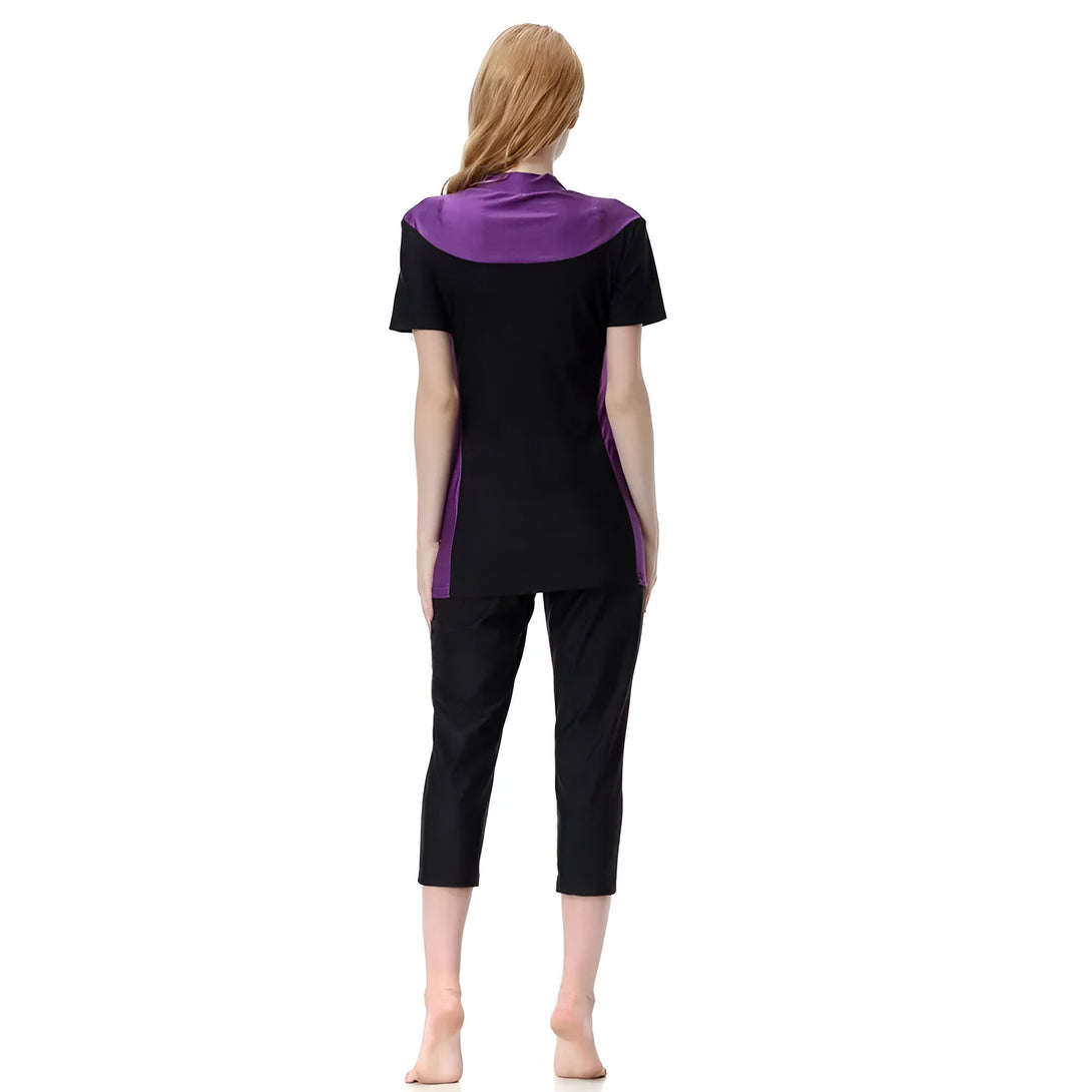 Une femme portant un ensemble de vêtements musulmans noir et violet, composé d'un haut à manches courtes et d'un pantalon.