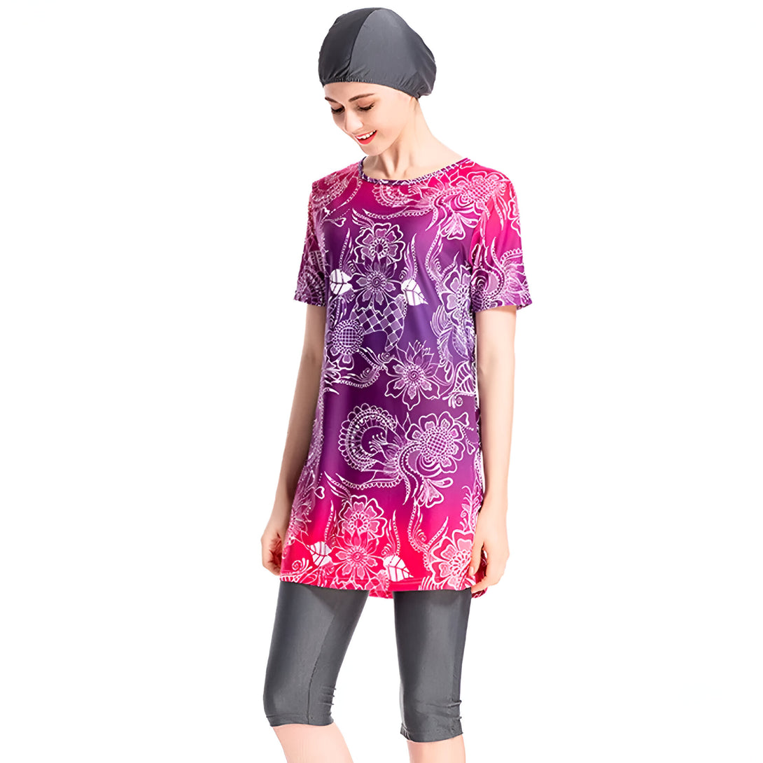 Une femme portant un maillot de bain musulman avec un motif floral en rose et violet, une écharpe grise et un pantalon gris.