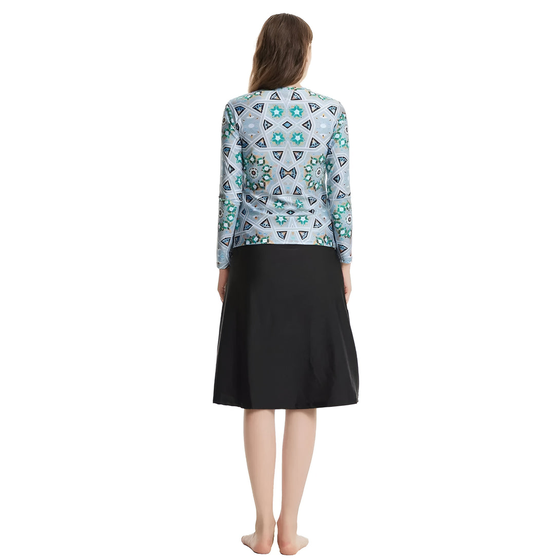 Une femme portant une jupe longue noire et un haut à manches longues avec un motif géométrique bleu et vert.