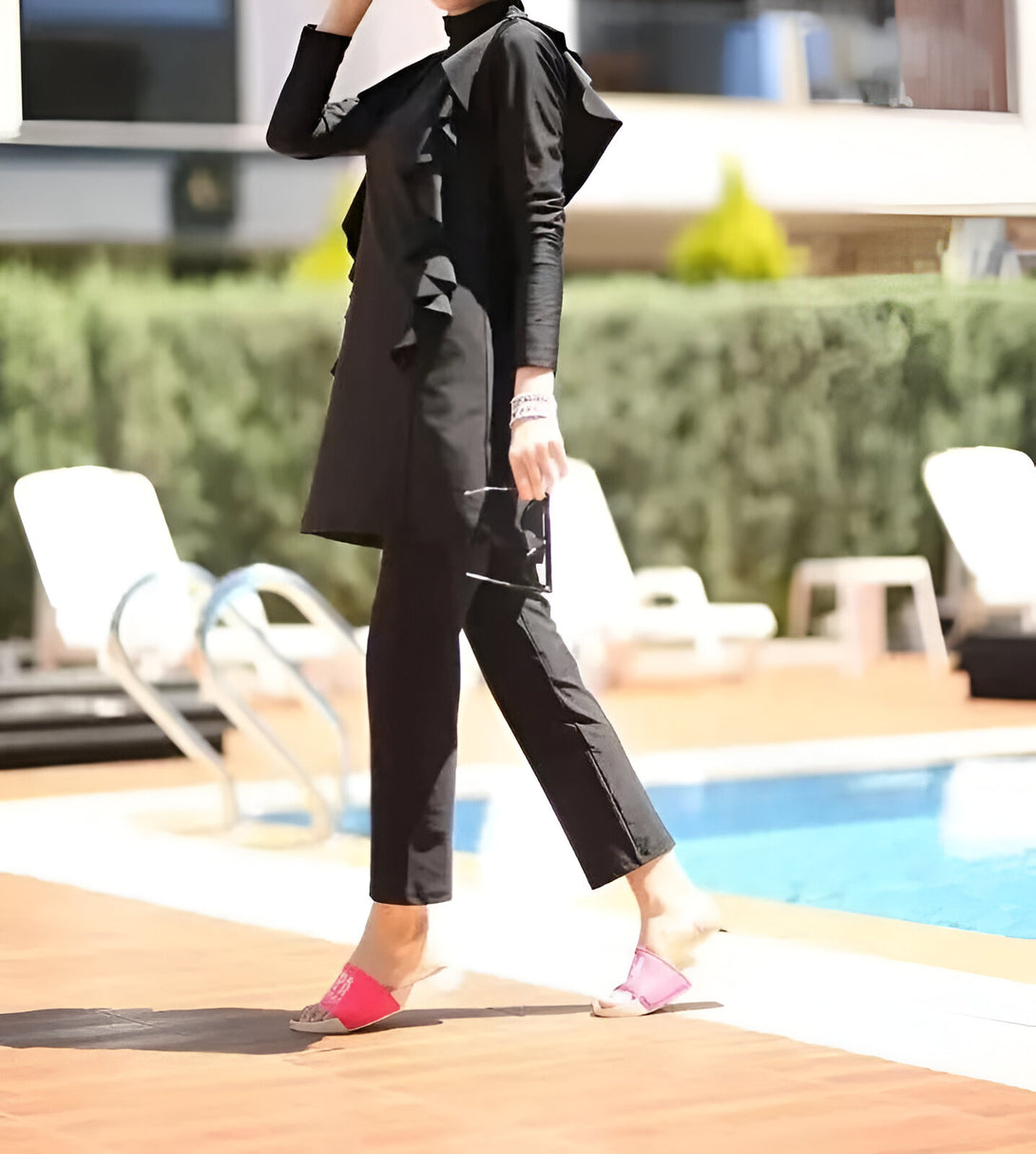Une femme portant un maillot de bain musulman noir avec des volants près d'une piscine.