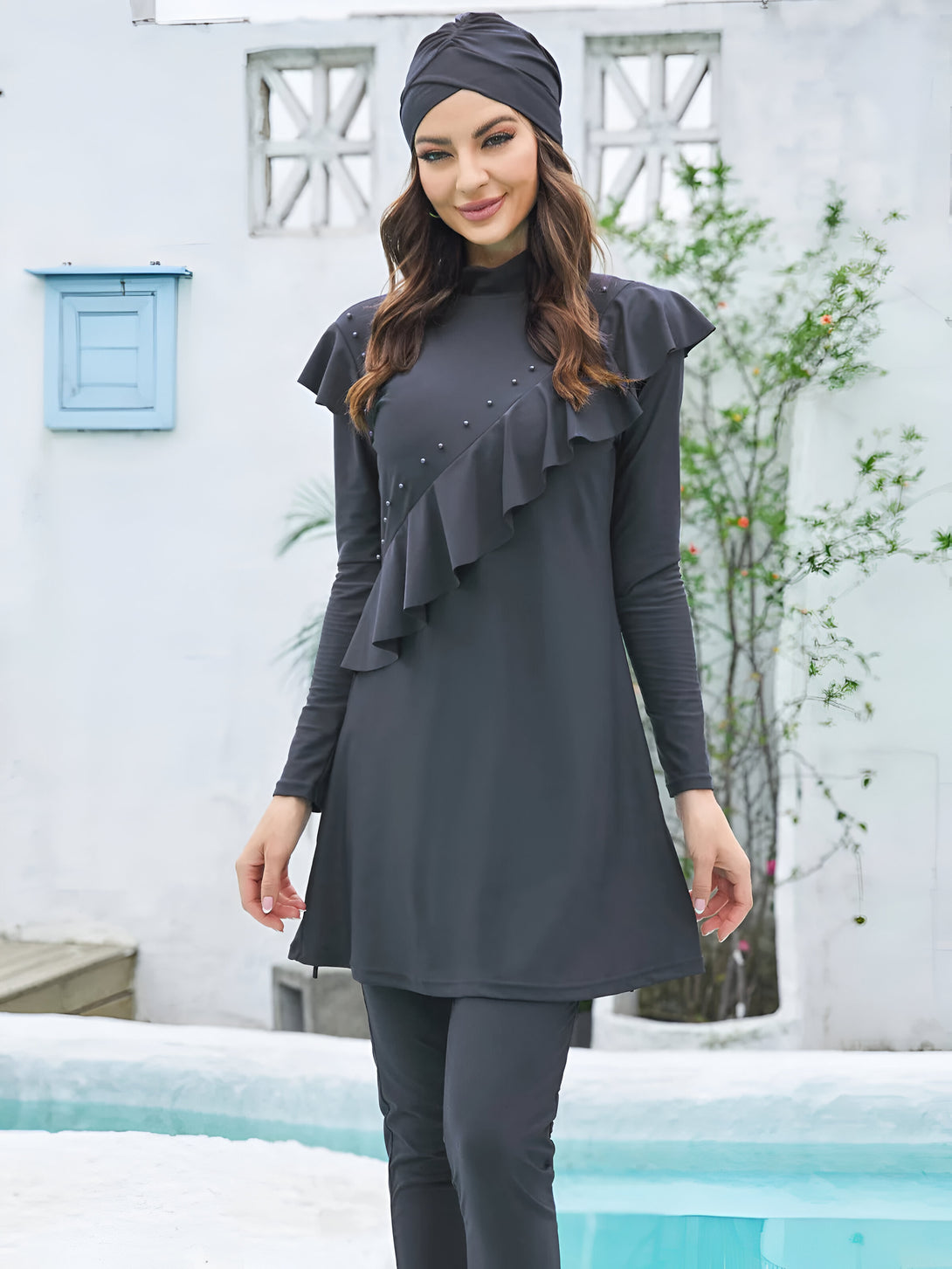 Une femme portant un hijab noir et un maillot de bain musulman noir à volants.