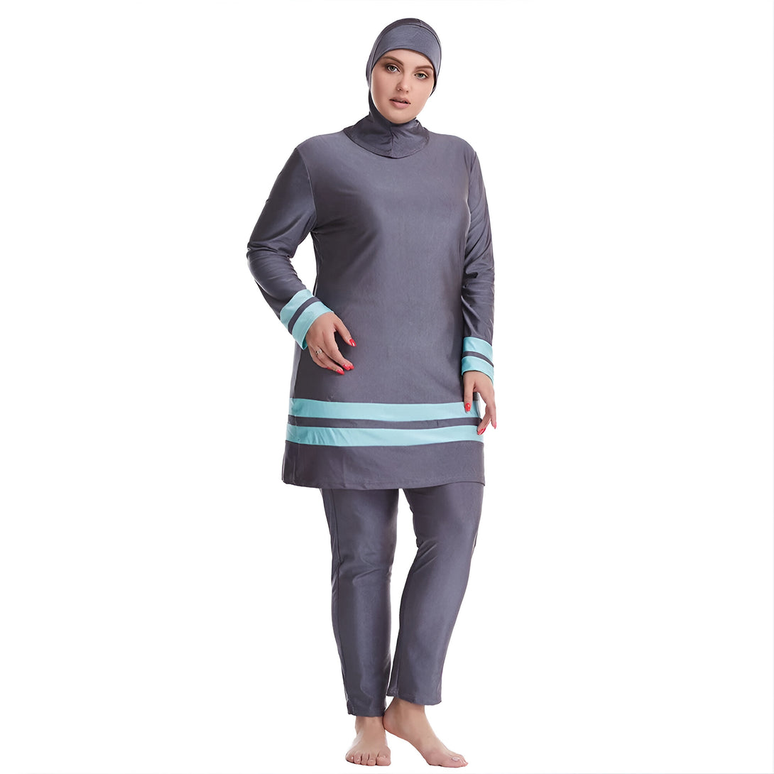 Une femme portant un maillot de bain musulman gris avec des bandes turquoise. Le maillot de bain comprend une tunique à manches longues et un pantalon long.