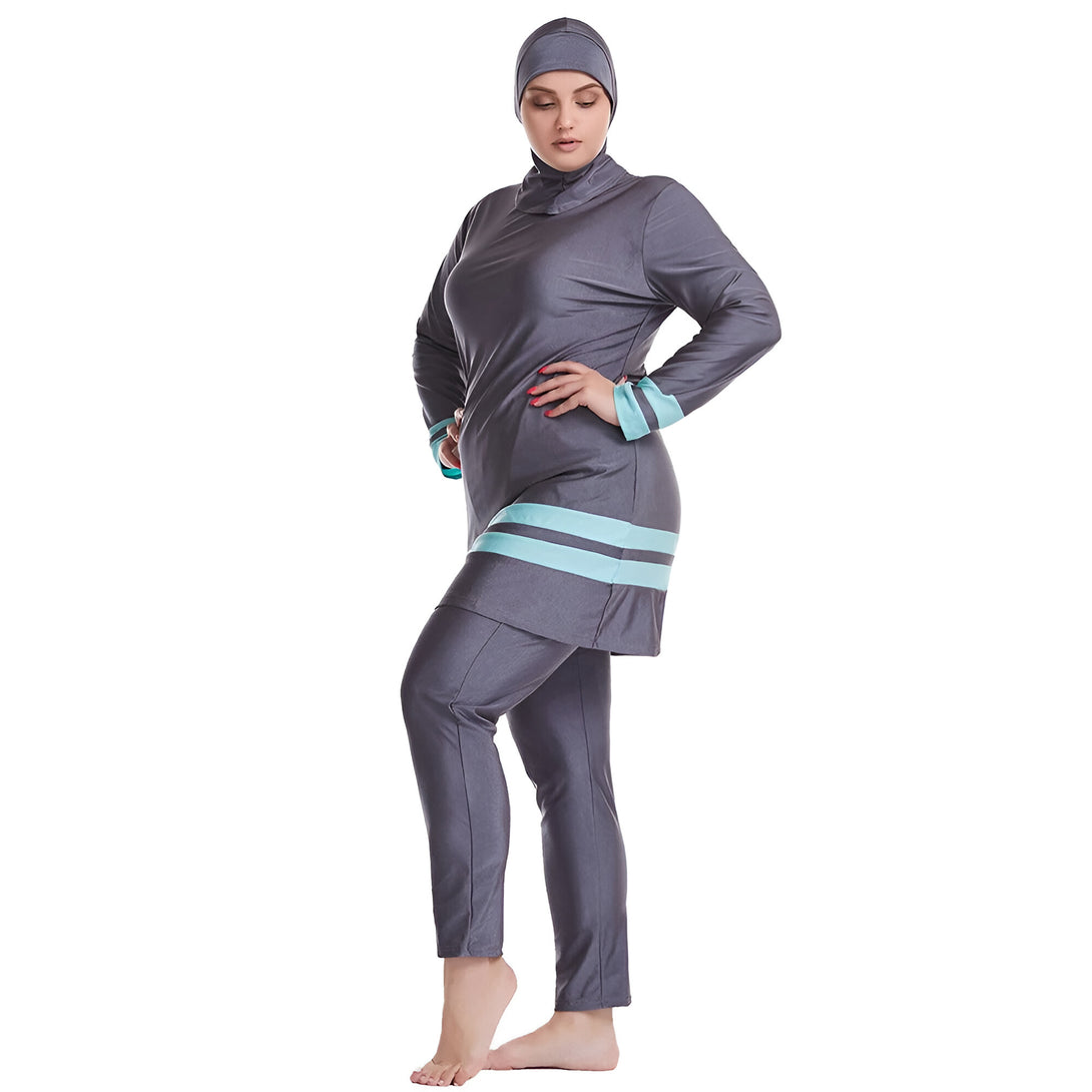 Une femme portant un maillot de bain musulman gris avec des bandes bleues. Le maillot de bain est à manches longues et couvre tout le corps. La femme porte un hijab assorti.
