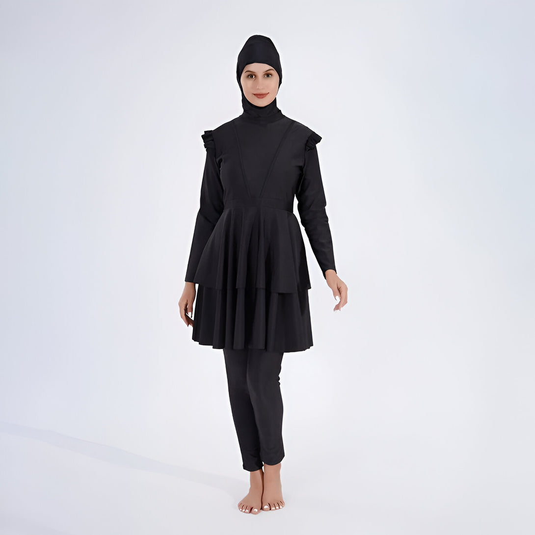 Une femme portant un maillot de bain musulman noir avec un hijab assorti. Le maillot de bain a des manches longues et une jupe à volants.