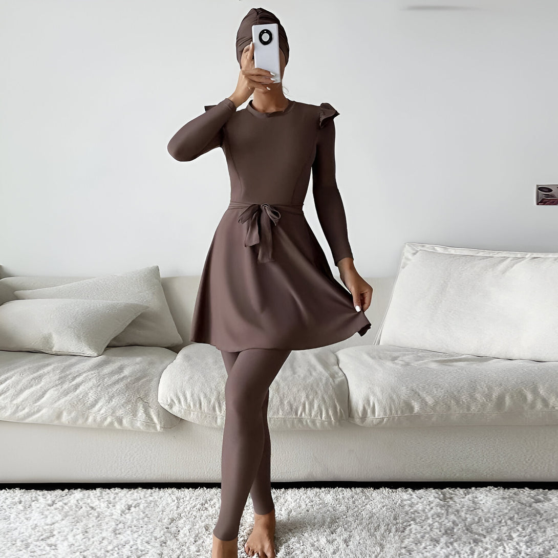 Une femme portant un maillot de bain musulman marron avec une jupe et un pantalon assortis, une ceinture et un foulard assorti.