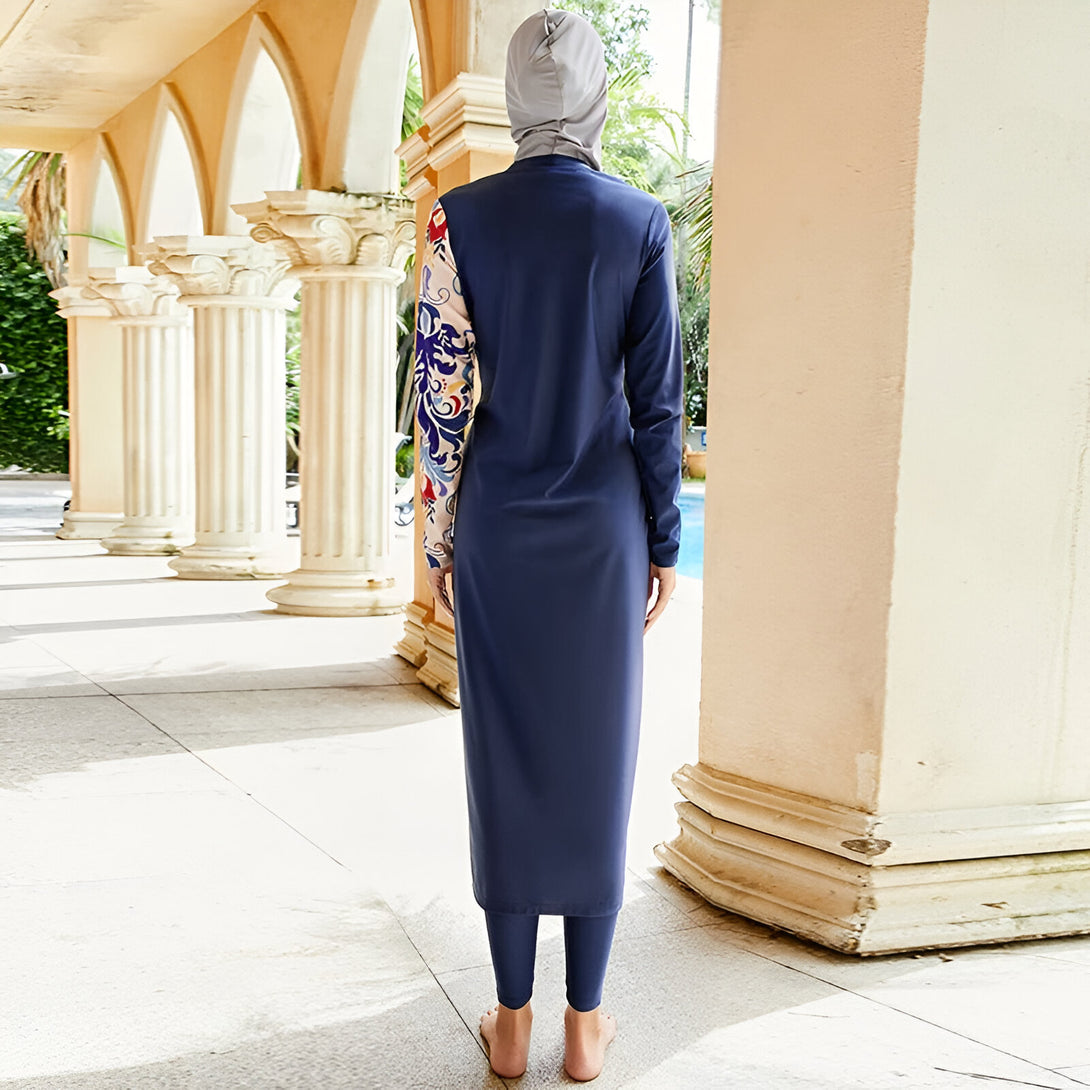 Une femme portant un maillot de bain islamique bleu marine avec des manches longues imprimées de motifs floraux.