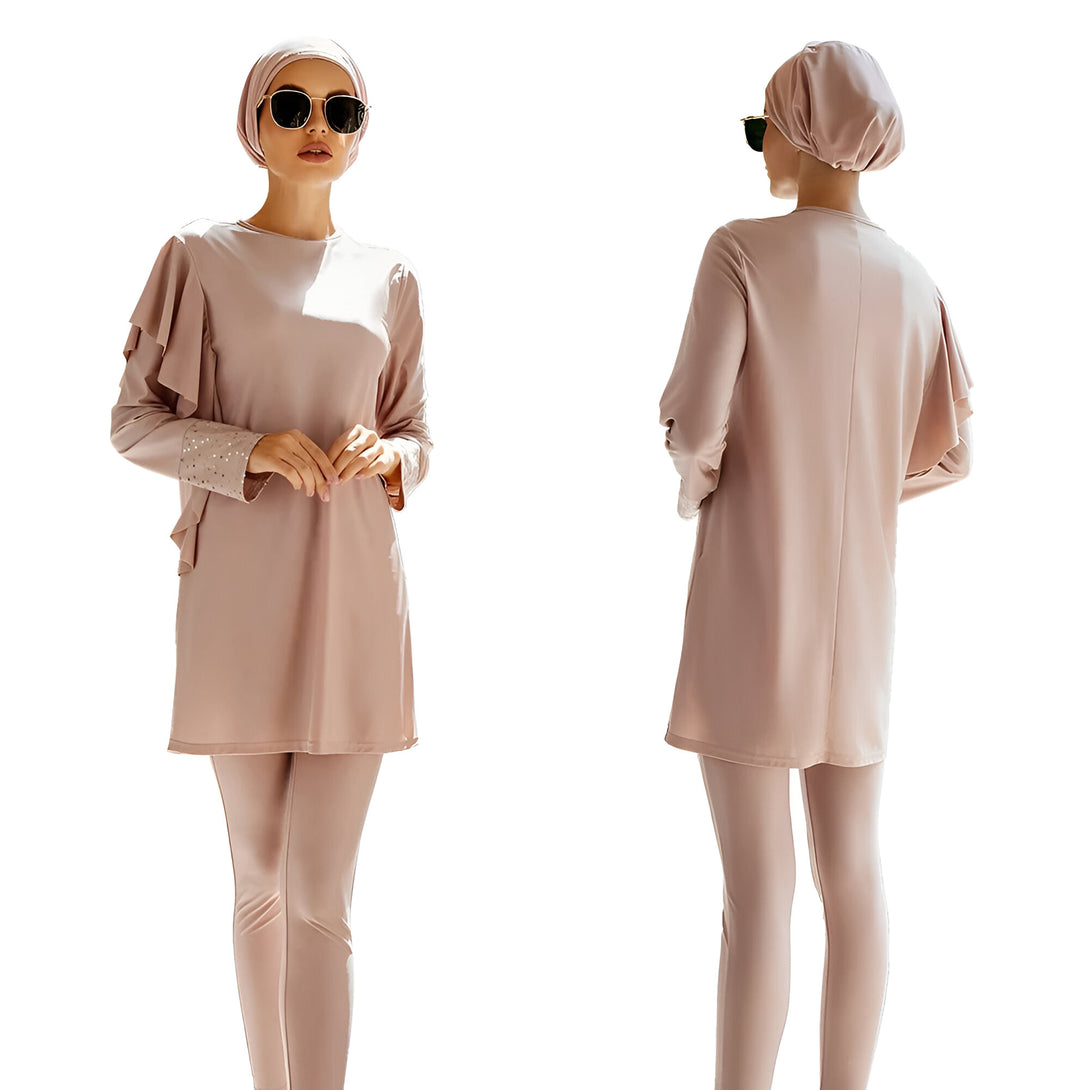 Une femme portant un hijab et un maillot de bain musulman rose. Le maillot de bain est composé d'un haut à manches longues avec un col rond et un pantalon long. La femme porte également des lunettes de soleil.