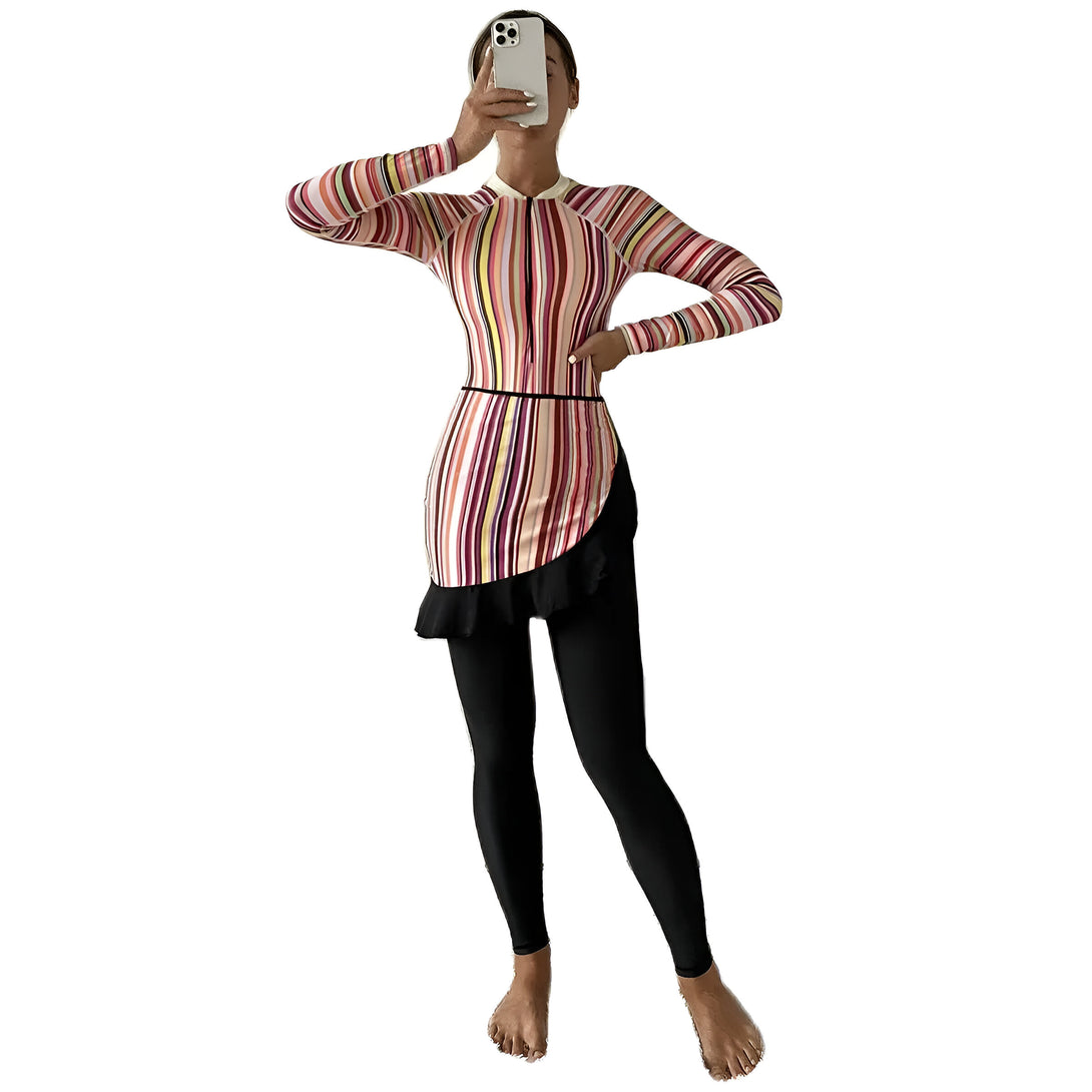 Une femme portant un maillot de bain musulman à rayures multicolores avec une jupe plissée et un pantalon noir.