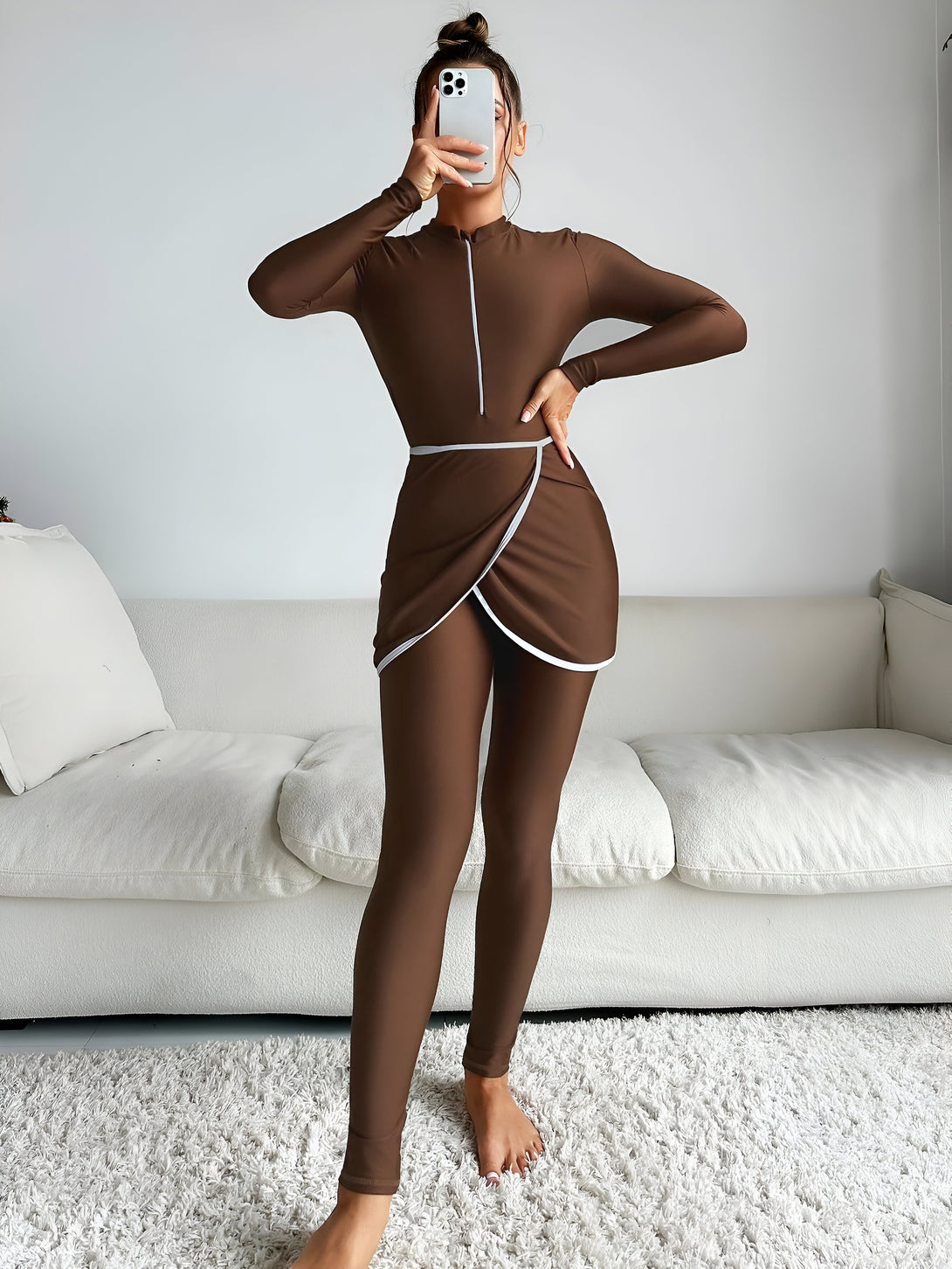 Une femme porte une tenue de bain musulmane marron avec une jupe enveloppante.