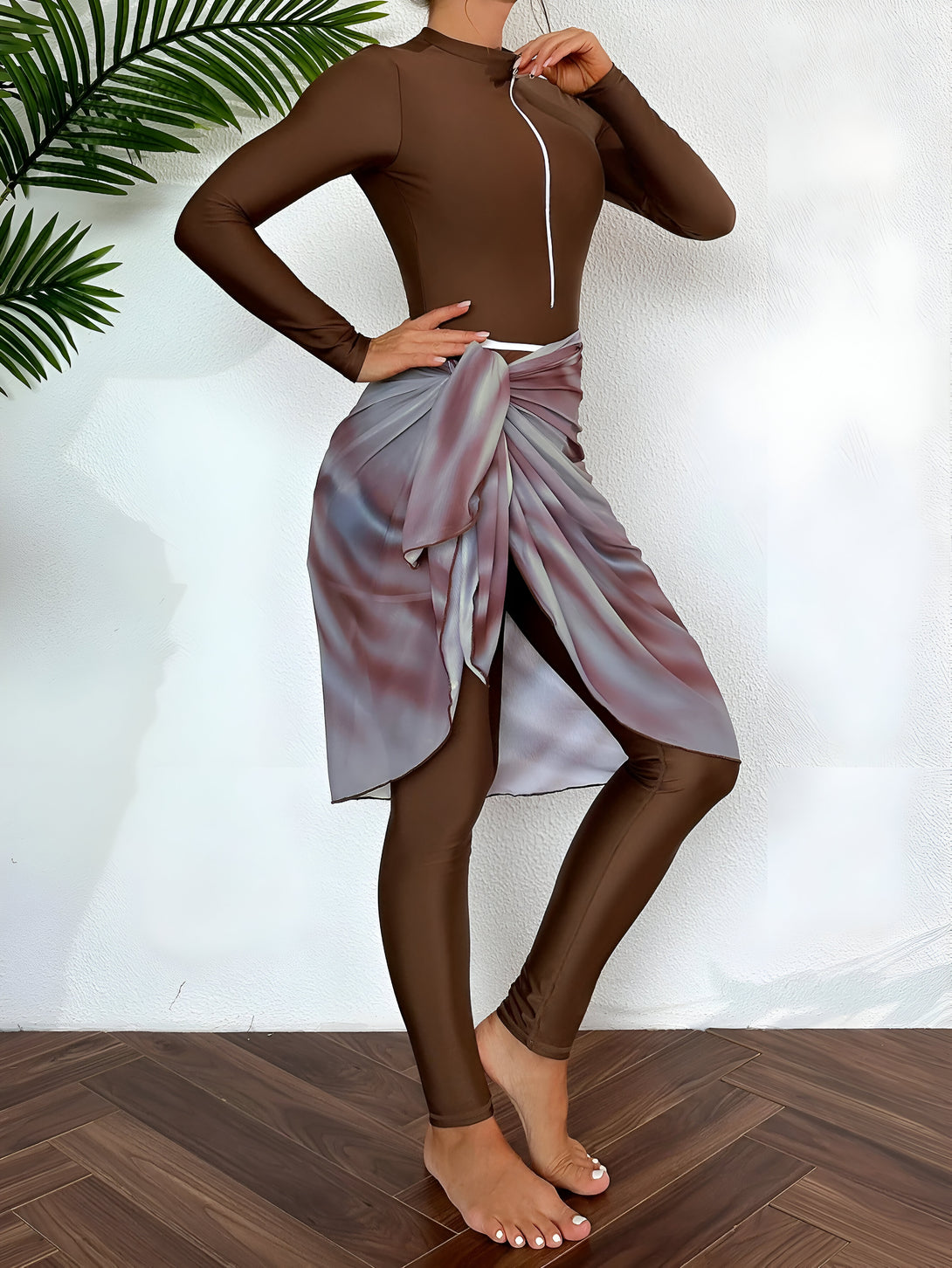 Une femme portant une tenue de bain musulmane marron avec une jupe en tissu fluide nouée à la taille.  Le tissu de la jupe a un imprimé marbré. La tenue est idéale pour la plage ou la piscine.