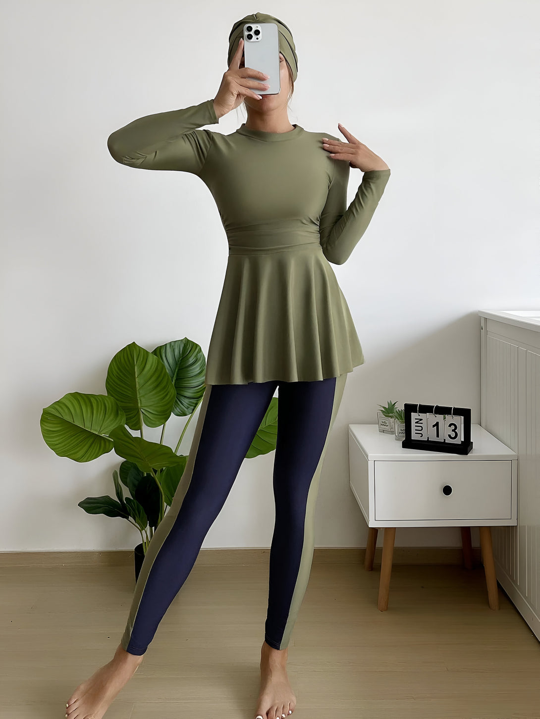 Une femme portant un hijab et un maillot de bain musulman vert kaki avec des leggings bleu marine.