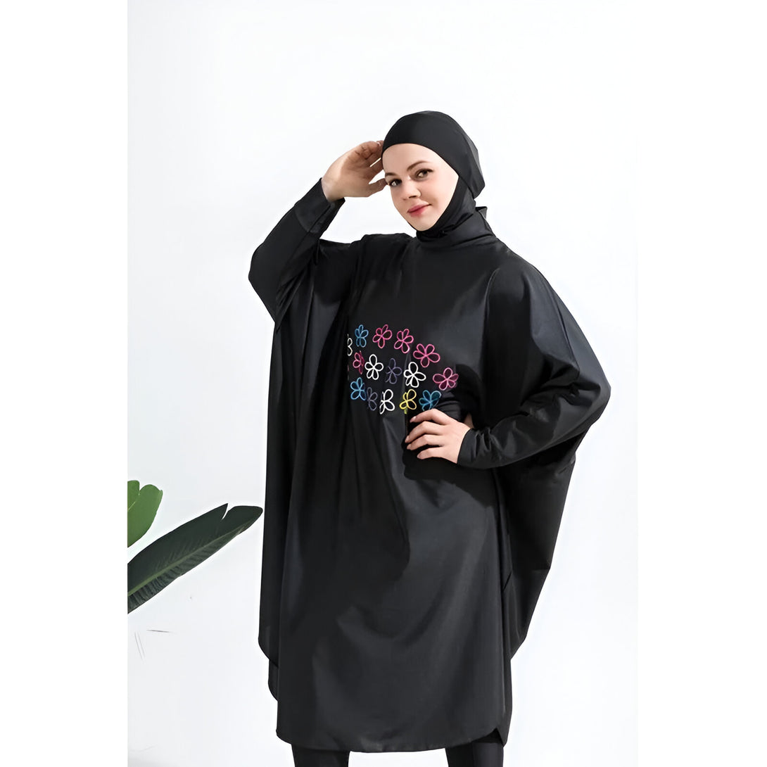 Une femme portant un maillot de bain musulman noir avec des fleurs colorées brodées.