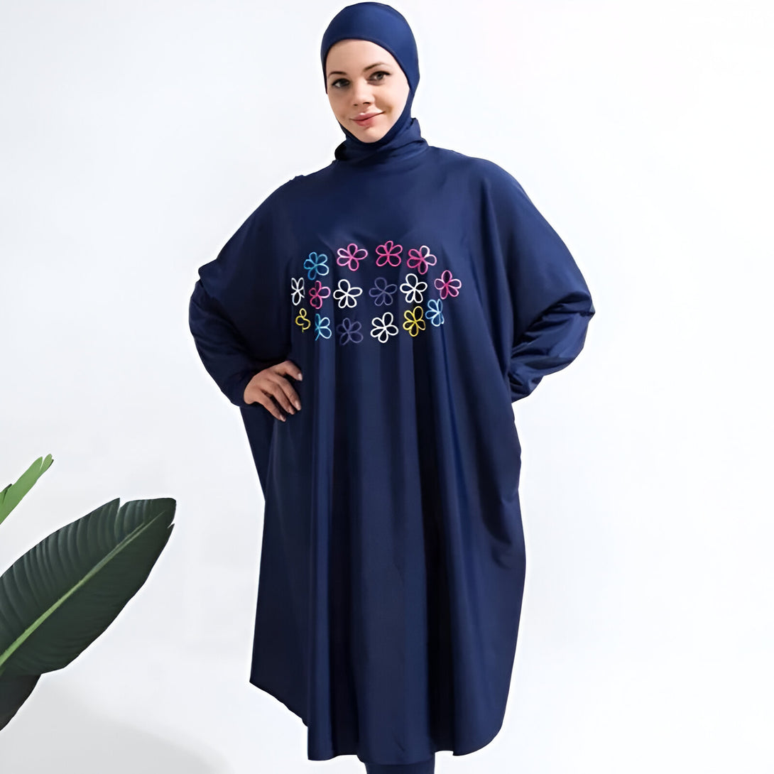 Une femme portant un maillot de bain musulman bleu marine avec des fleurs multicolores brodées.