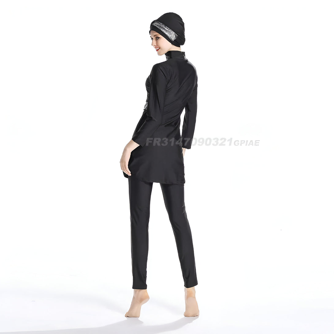 Une femme portant un hijab noir et un maillot de bain musulman noir. Le maillot de bain est composé d'une tunique à manches longues et d'un pantalon long.