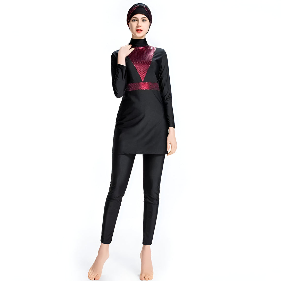 Une femme porte un maillot de bain musulman noir avec un haut à manches longues et un pantalon. Le haut a une bande rouge pailletée sur la poitrine. Elle porte également un hijab noir.