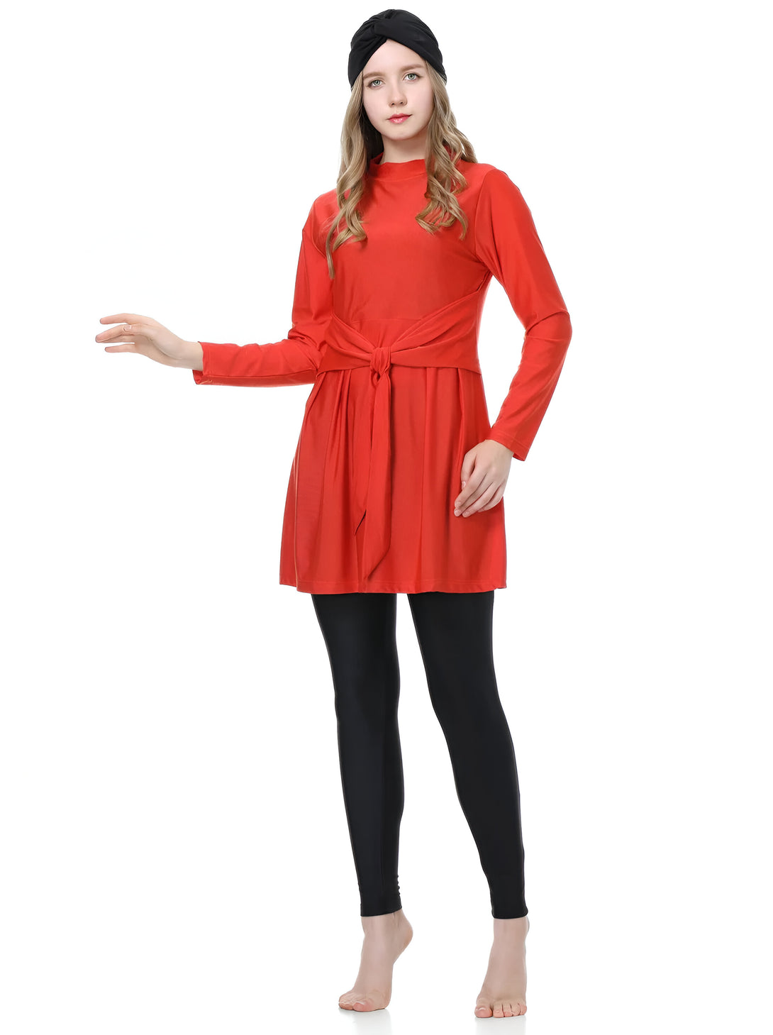 Une femme portant un hijab noir et une robe rouge avec un noeud à la taille, ainsi que des leggings noirs.