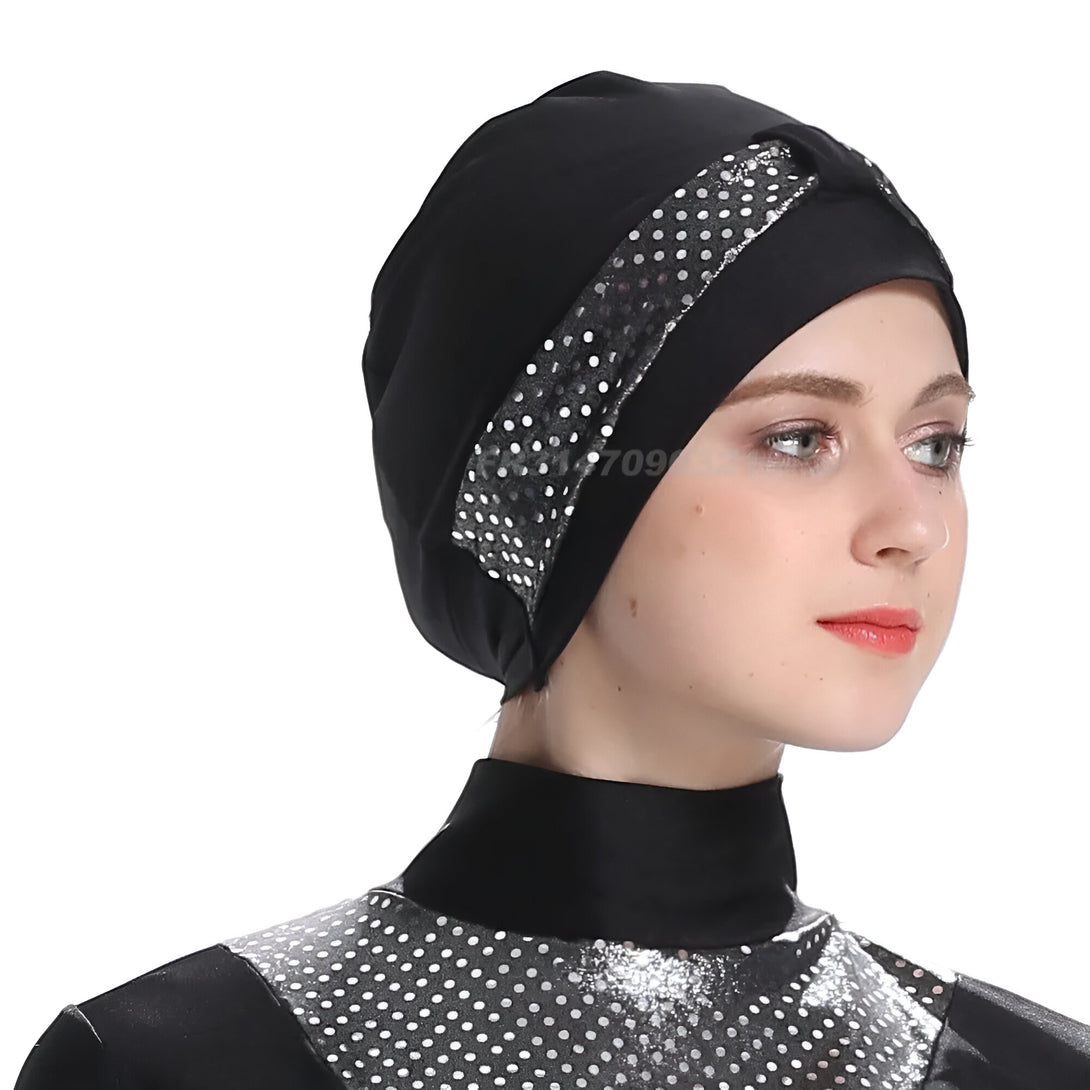 Une femme portant un hijab noir avec des paillettes argentées et une combinaison de bain noire à pois argentés.