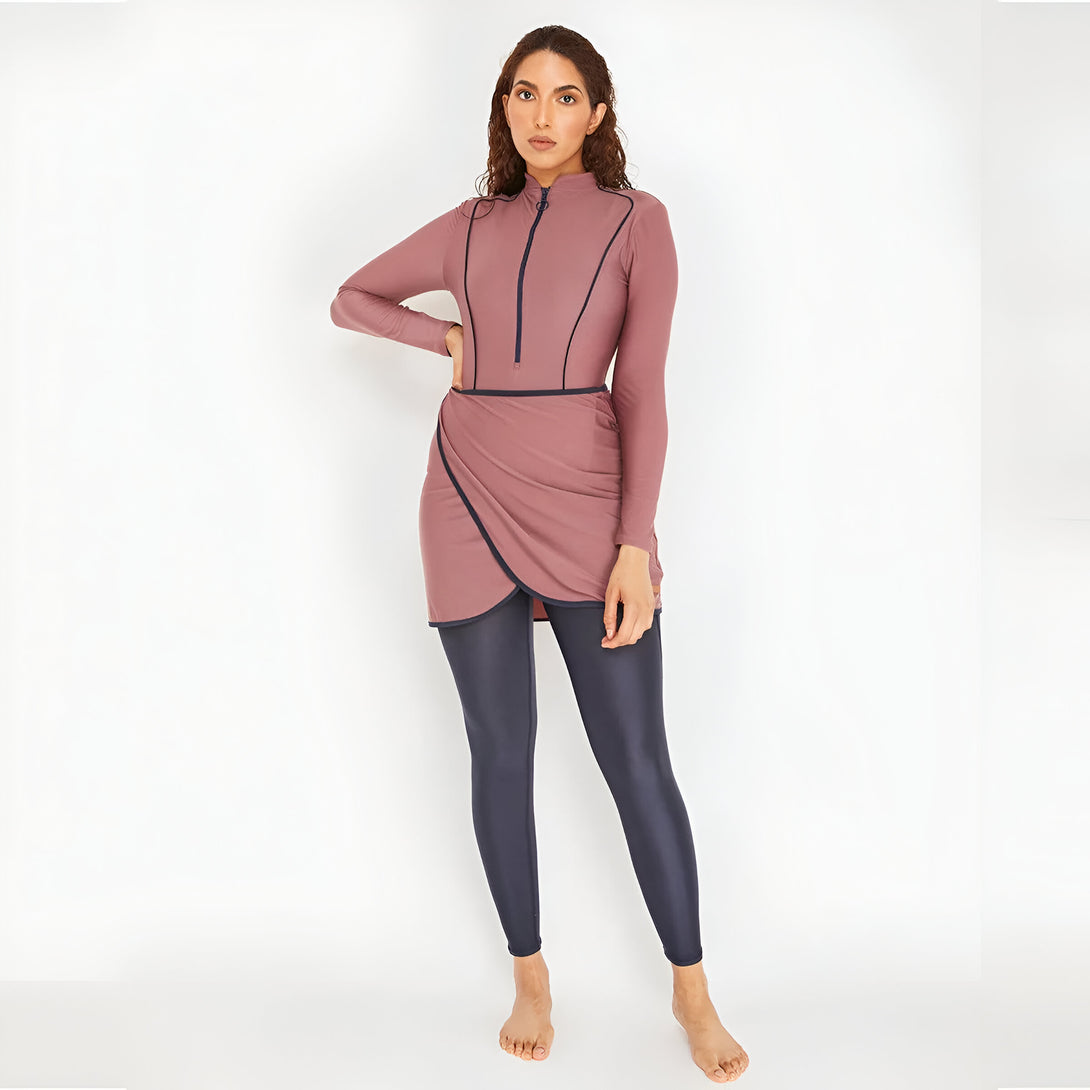 Une femme portant un maillot de bain musulman rose avec une jupe intégrée et des leggings noirs.