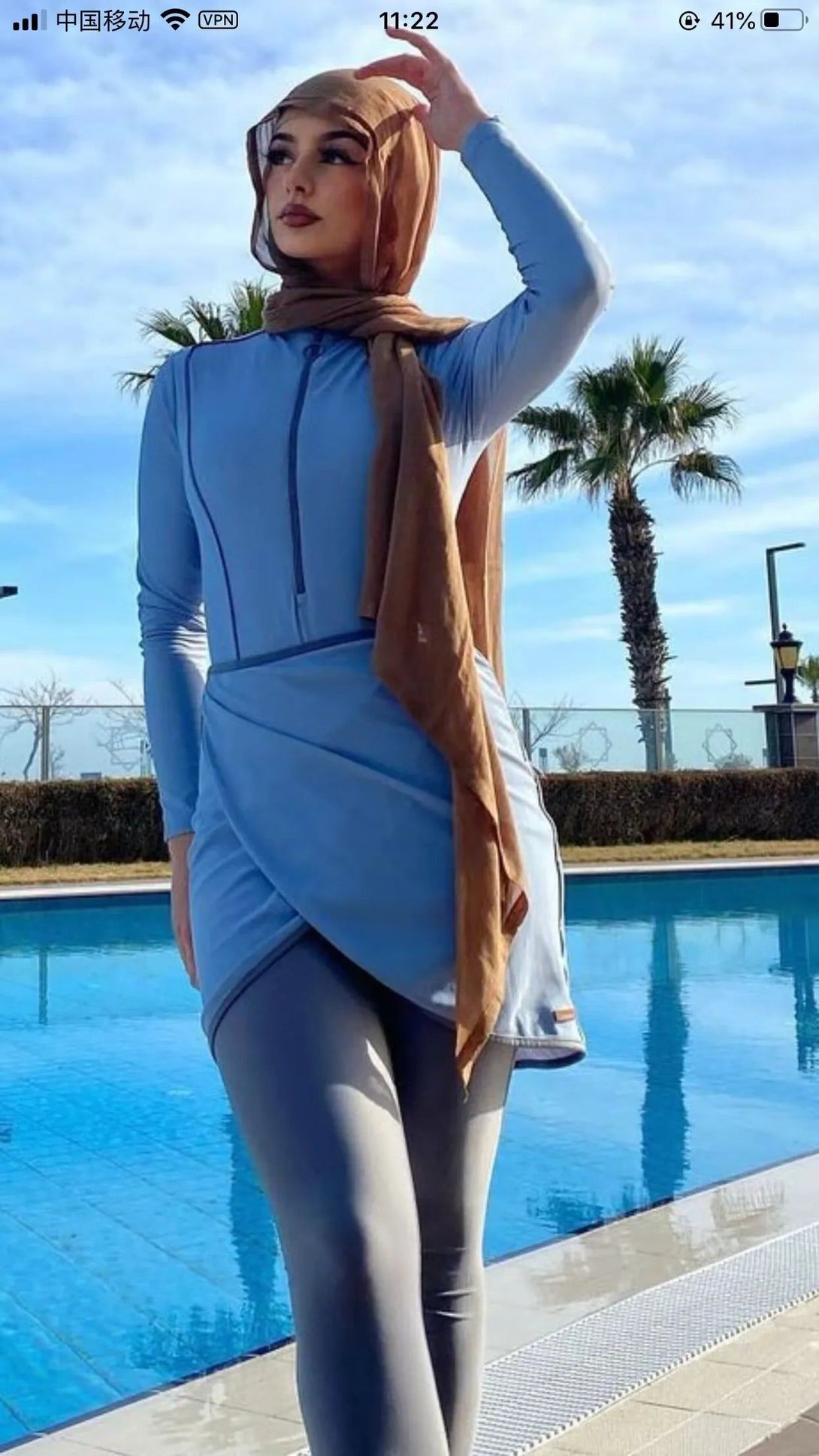 Une femme portant un hijab et un maillot de bain islamique bleu près d'une piscine.