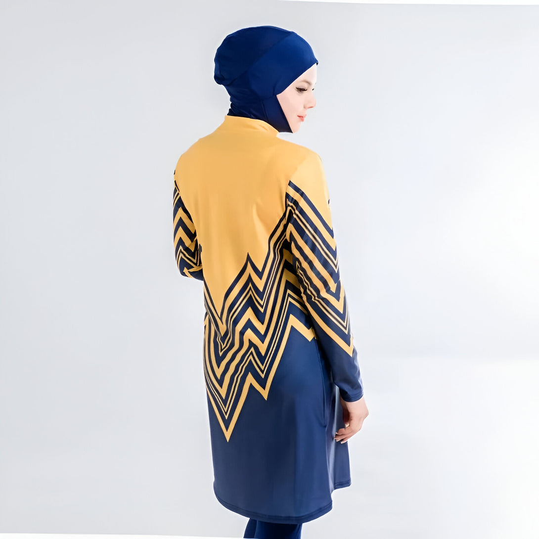 Une femme portant un hijab bleu foncé et une robe de bain musulmane jaune et bleue avec un motif géométrique.