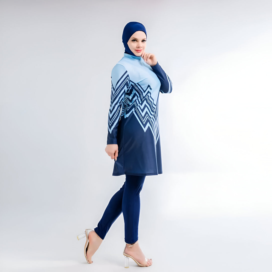 Une femme portant un maillot de bain musulman bleu et blanc avec un motif géométrique. Elle porte un hijab assorti et des talons hauts.