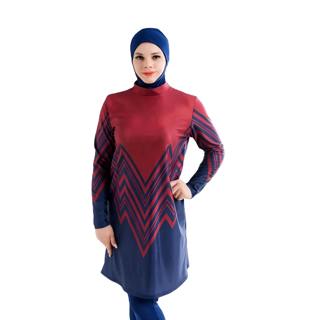 Une femme portant un maillot de bain musulman bleu et rouge avec un motif géométrique.  Le maillot est à manches longues et couvre tout le corps. La femme porte également un hijab bleu.