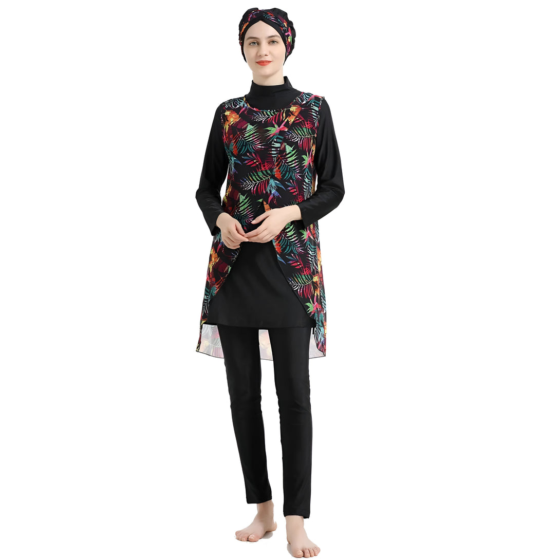 Une femme portant un maillot de bain musulman noir avec un motif floral coloré. Le maillot de bain comprend une tunique à manches longues et un pantalon long. La femme porte également un hijab assorti.