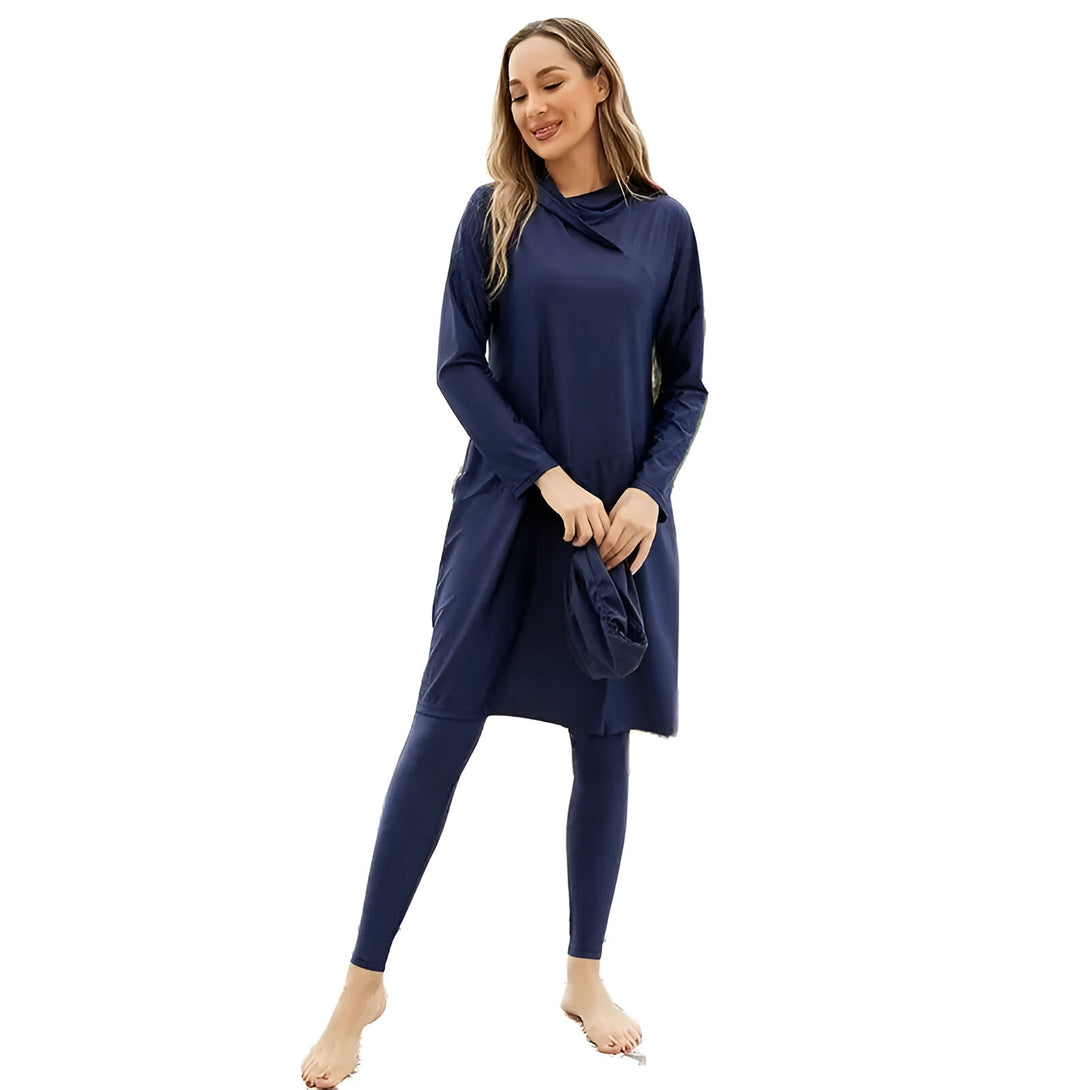 Une femme portant un maillot de bain islamique bleu marine avec une robe longue, un pantalon long et un bonnet assorti.