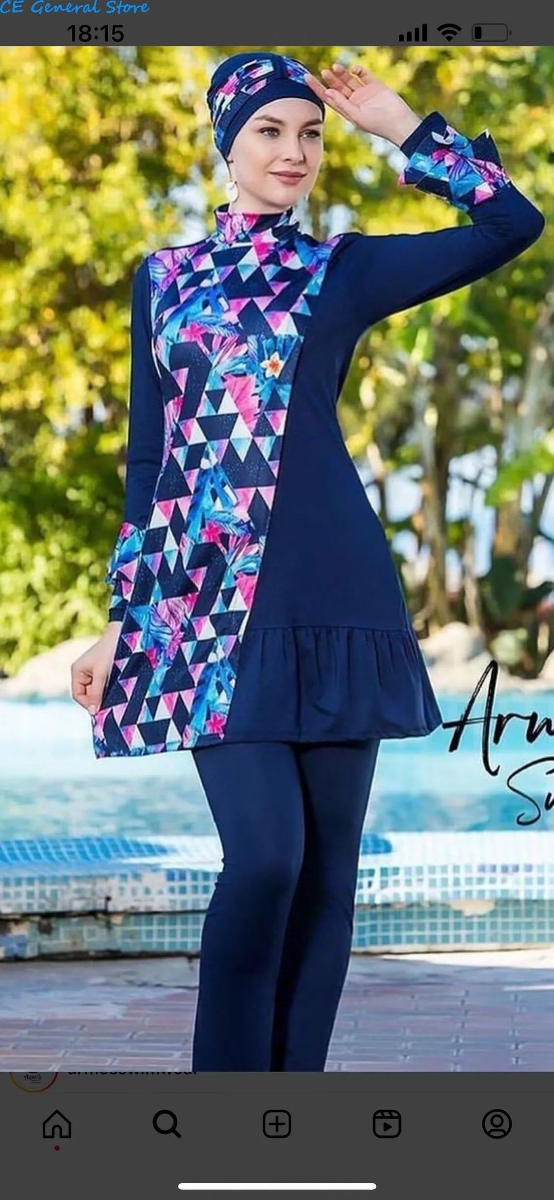 Une femme portant un maillot de bain musulman bleu marine et imprimé de triangles et de fleurs. Le maillot de bain a des manches longues et une jupe courte. La femme porte également un hijab bleu marine.