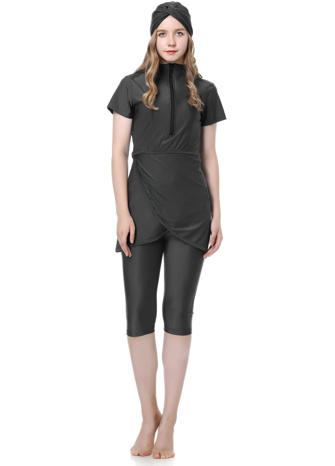 Une femme porte un maillot de bain musulman noir avec une fermeture éclair sur le devant, des manches courtes et des leggings. Elle porte également un turban noir sur la tête.