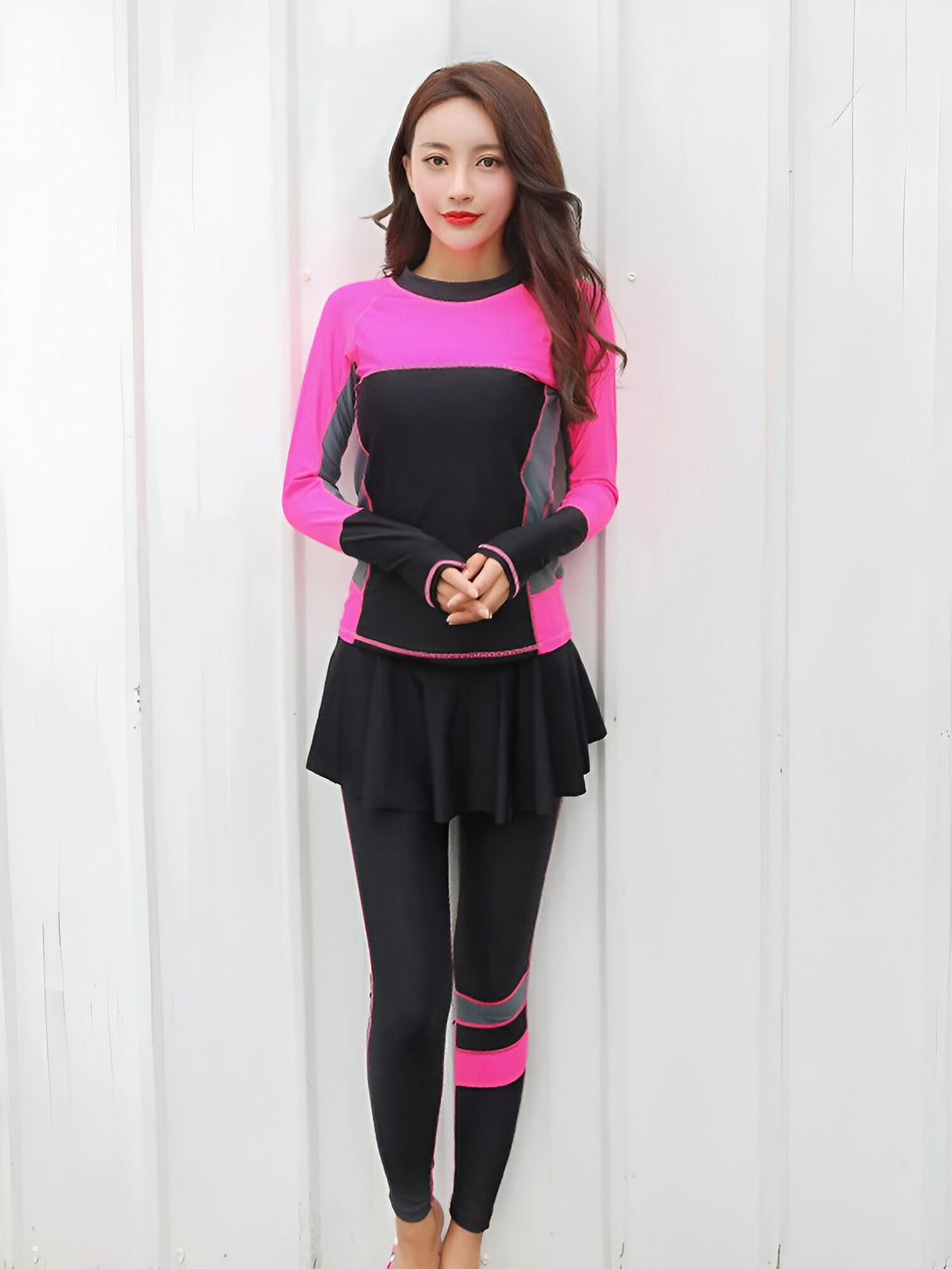 Une femme porte un ensemble de vêtements de sport musulmans noir et rose avec une jupe intégrée.