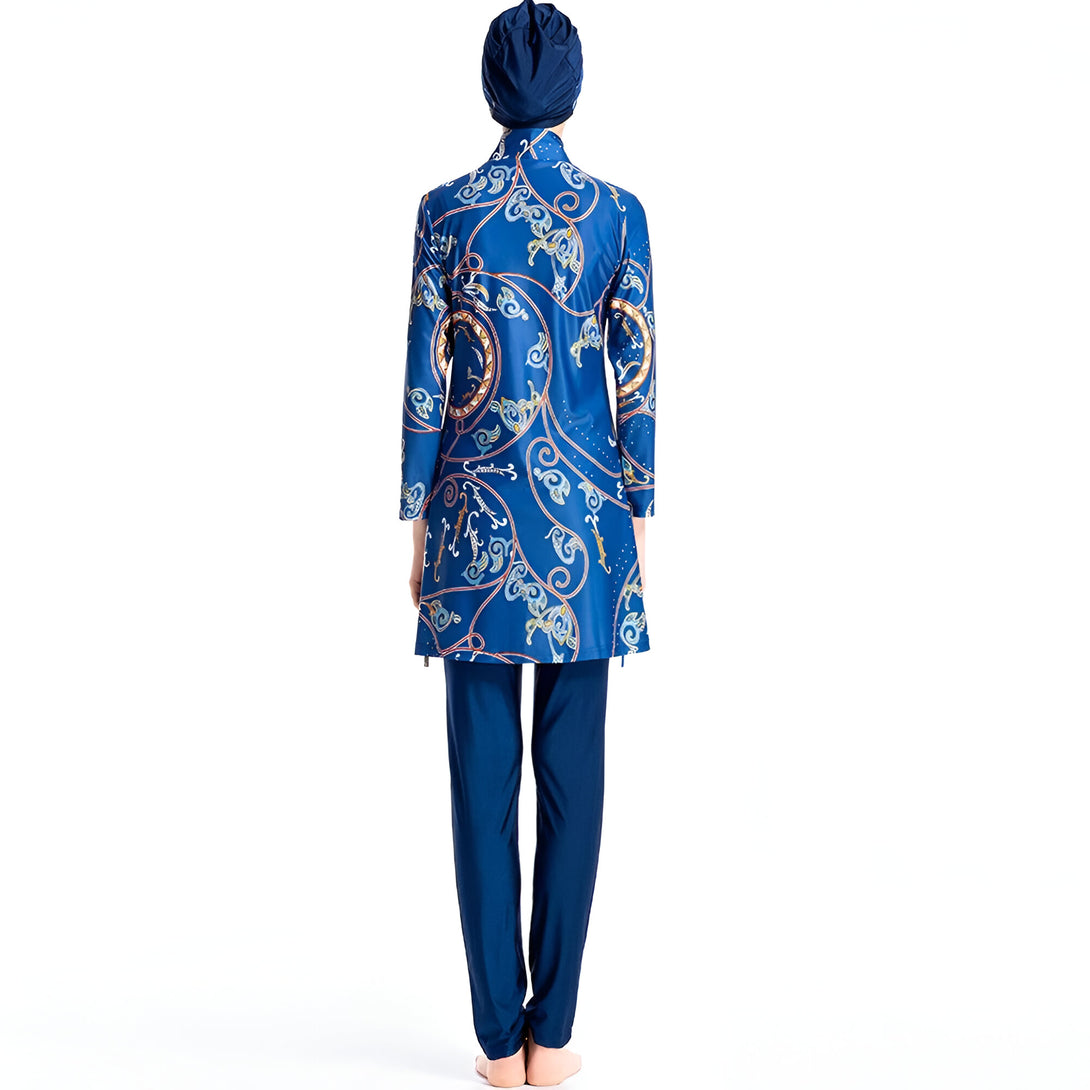Une femme portant un maillot de bain musulman bleu à motifs dorés. Le maillot de bain est à manches longues et couvre les jambes.  La femme porte un hijab bleu assorti.