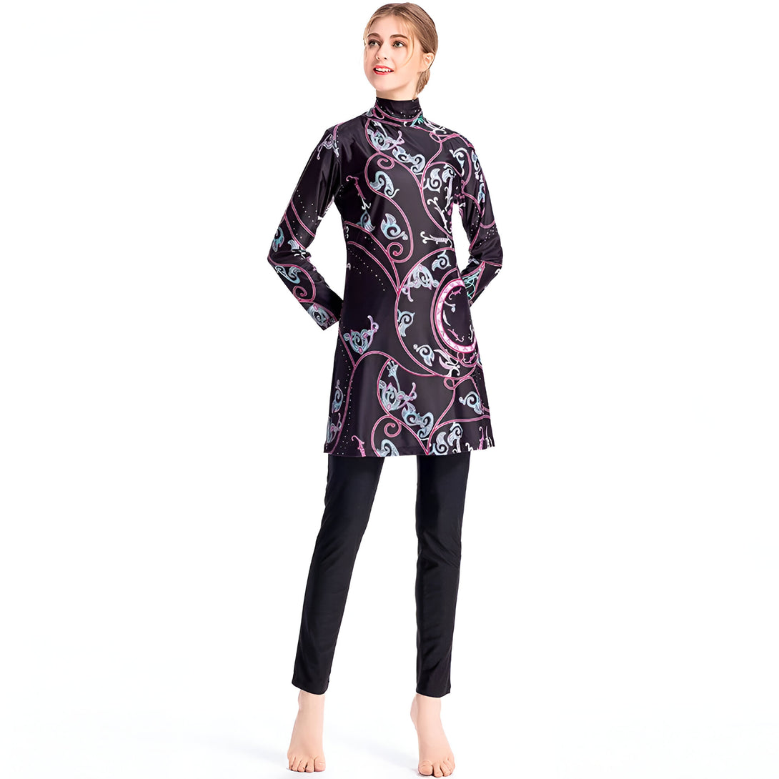 Une femme portant un maillot de bain musulman noir à manches longues avec un motif floral rose et bleu. Le maillot de bain est composé d'une tunique et d'un pantalon.