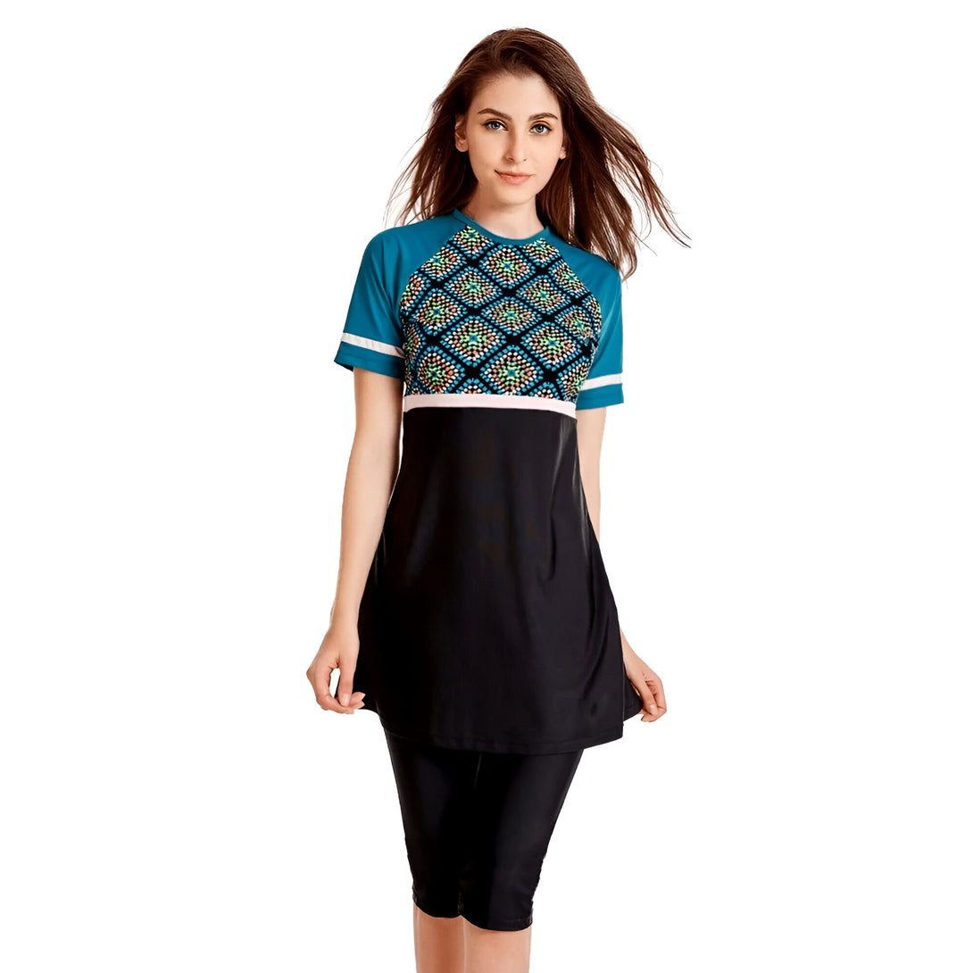 Une femme portant un maillot de bain musulman à manches courtes avec un motif géométrique bleu et noir. Le maillot de bain est composé d'une tunique et d'un pantalon long.