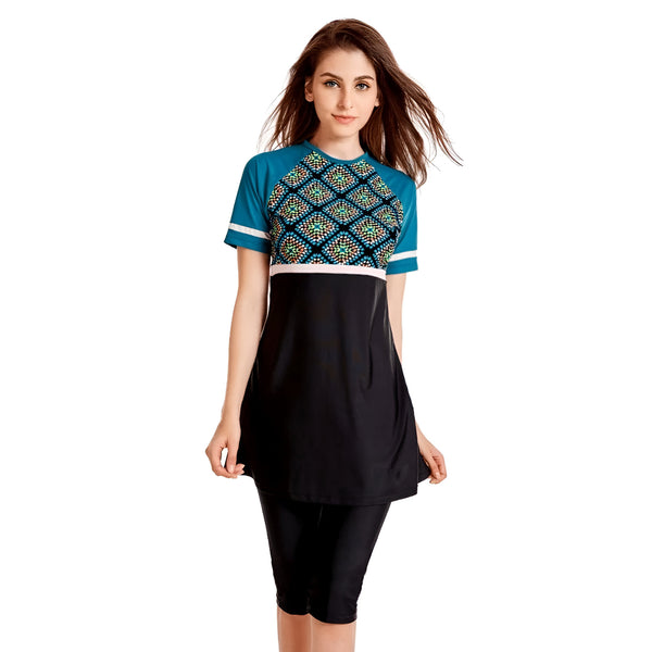 Une femme portant un maillot de bain musulman à manches courtes avec un motif géométrique bleu et noir. Le maillot de bain est composé d'une tunique et d'un pantalon long.