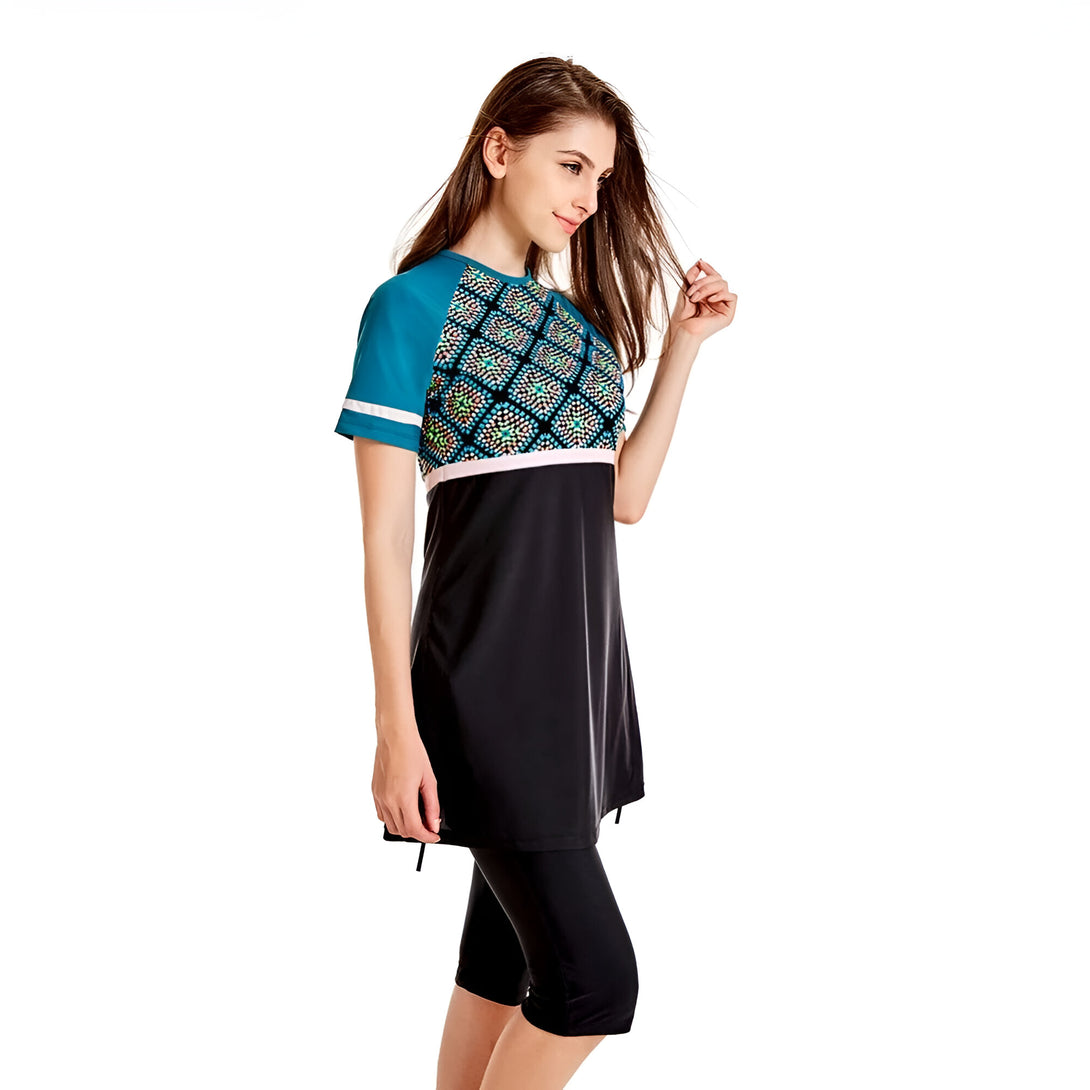 Une femme portant un maillot de bain musulman noir avec une chemise à manches courtes bleu turquoise et un motif géométrique.
